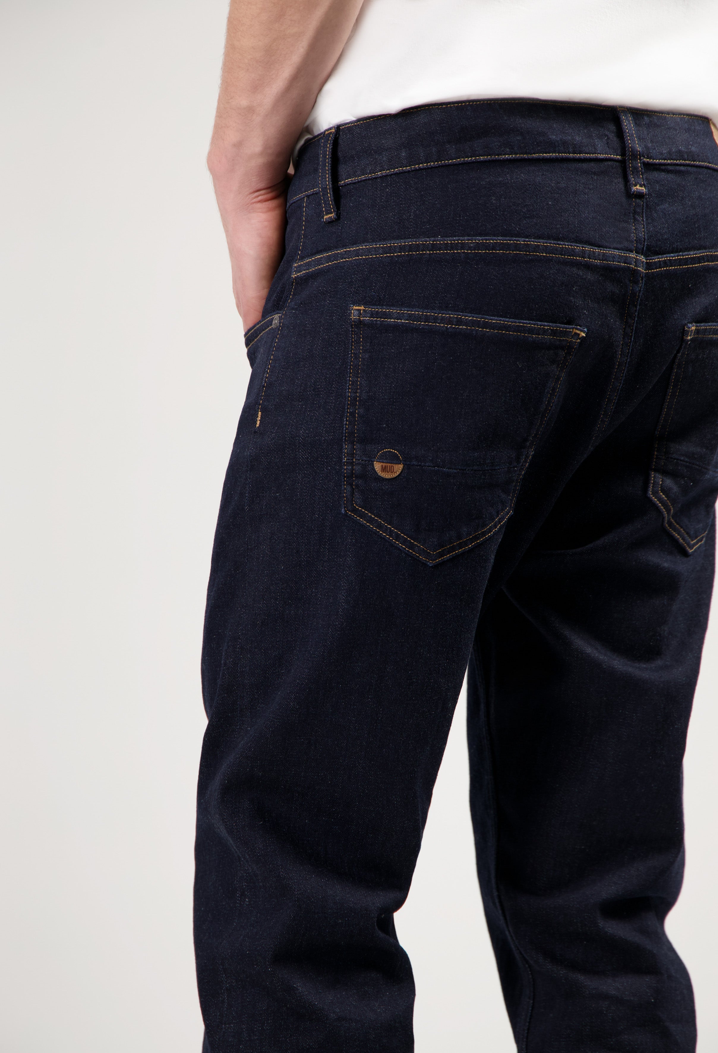 Eco-friendly MUD Jeans in blue denim, designed for a sustainable lifestyle, paired with a dark gray sweater.