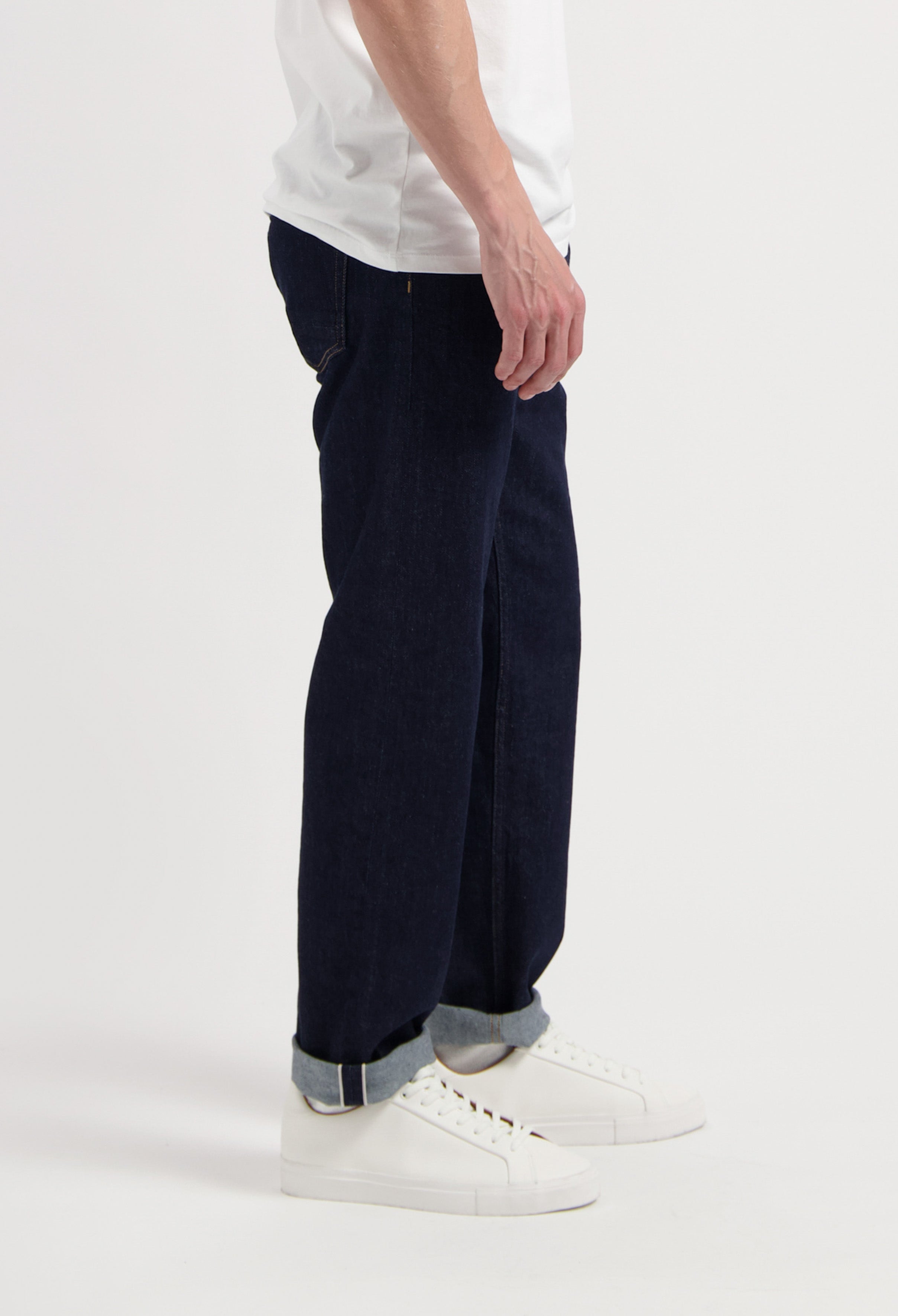 Sustainable MUD Jeans crafted from organic cotton, featuring dark blue denim in a regular fit, paired with a gray sweater.