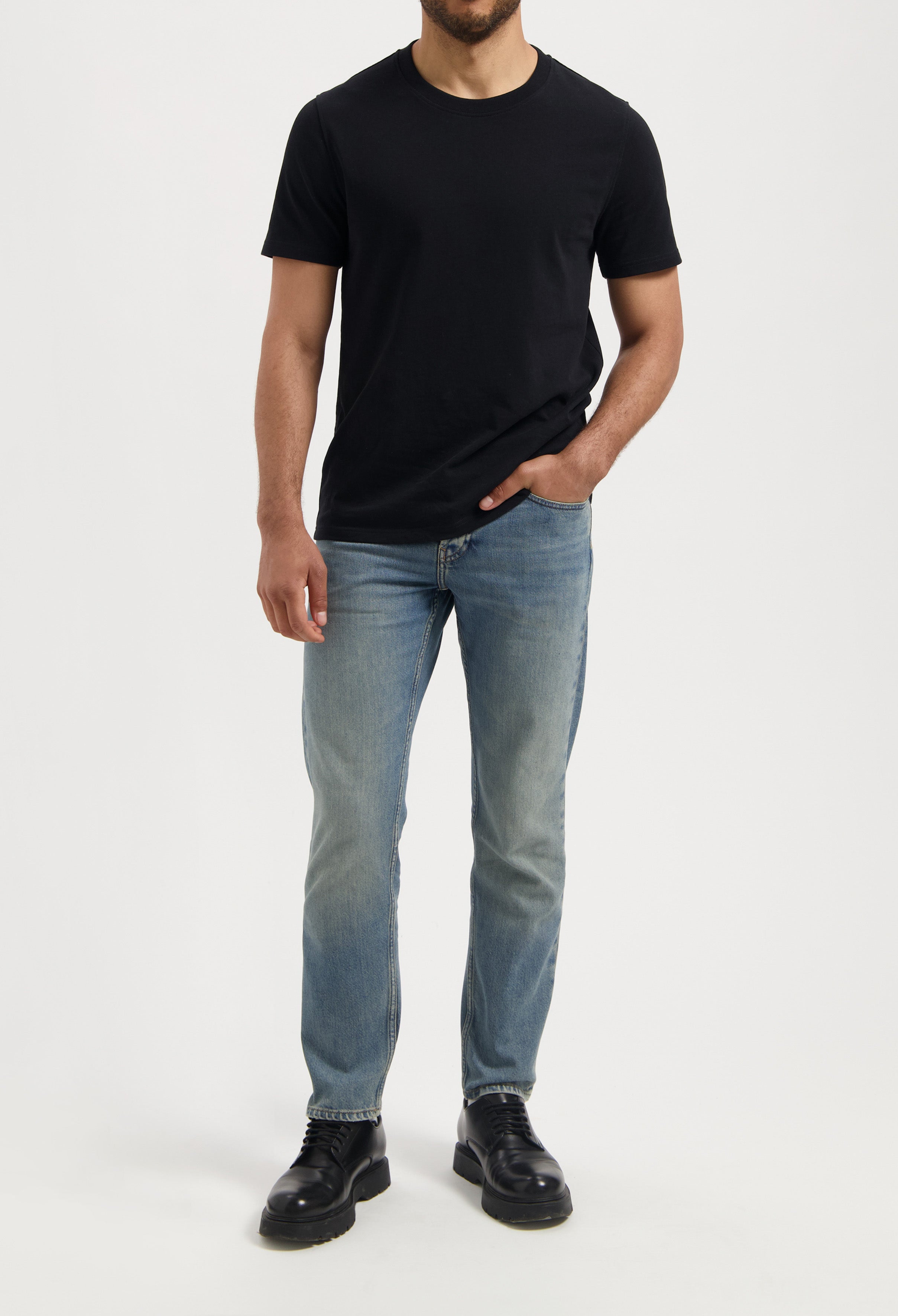 Sustainable MUD Jeans navy shorts made from organic cotton, paired with a dark blue shirt and white sneakers.