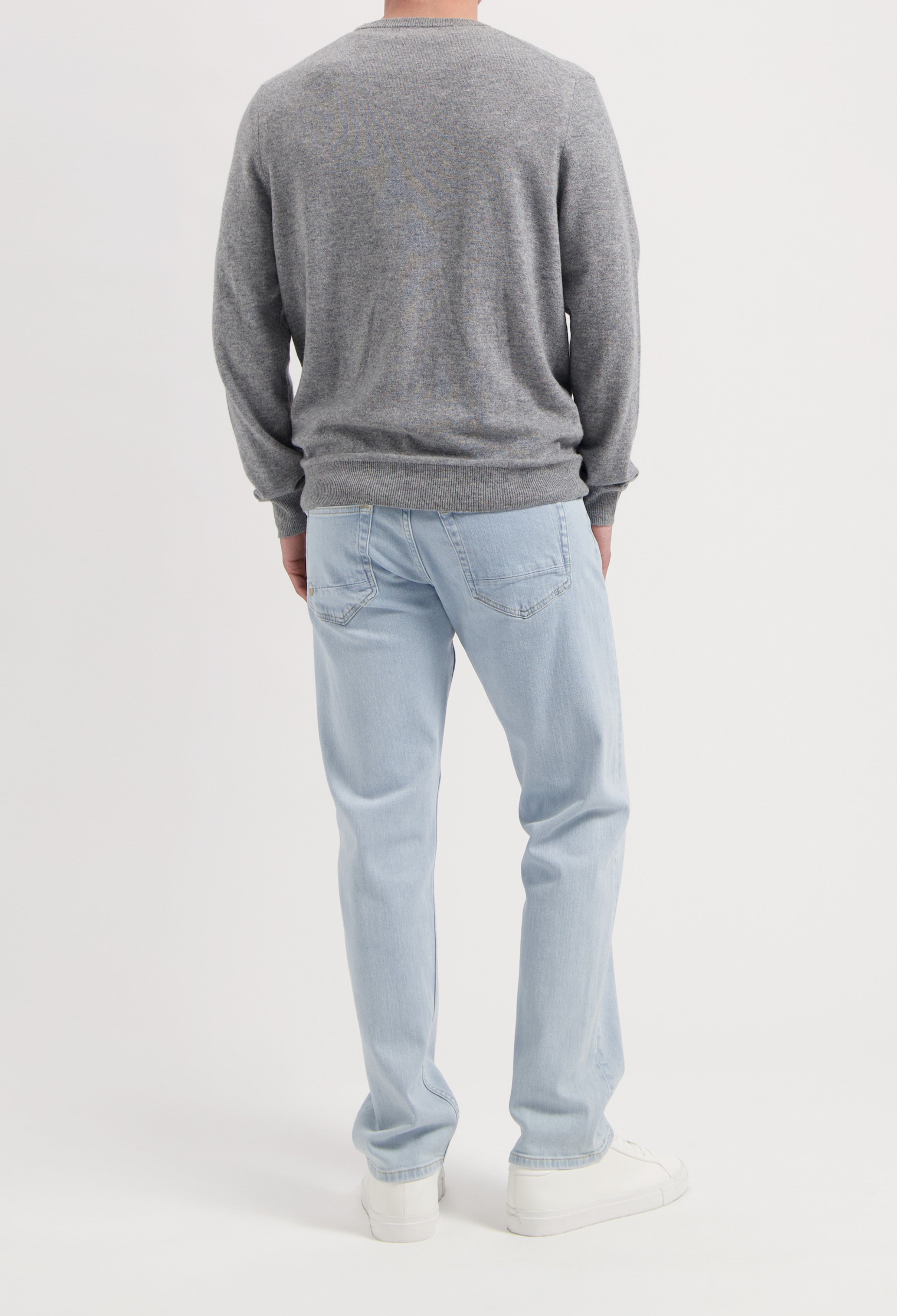 Sustainable MUD Jeans in gray, crafted from organic cotton, offering a classic straight fit, paired with black sneakers.