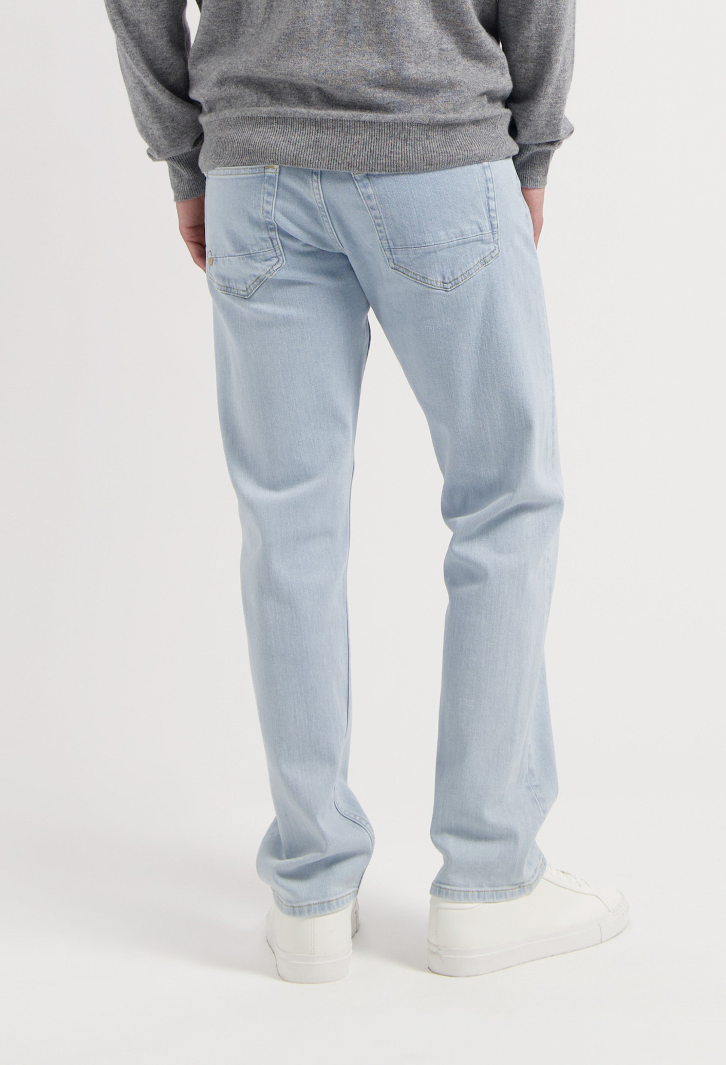 Sustainable MUD Jeans in light gray denim, crafted ethically from organic cotton, shown with a black top.