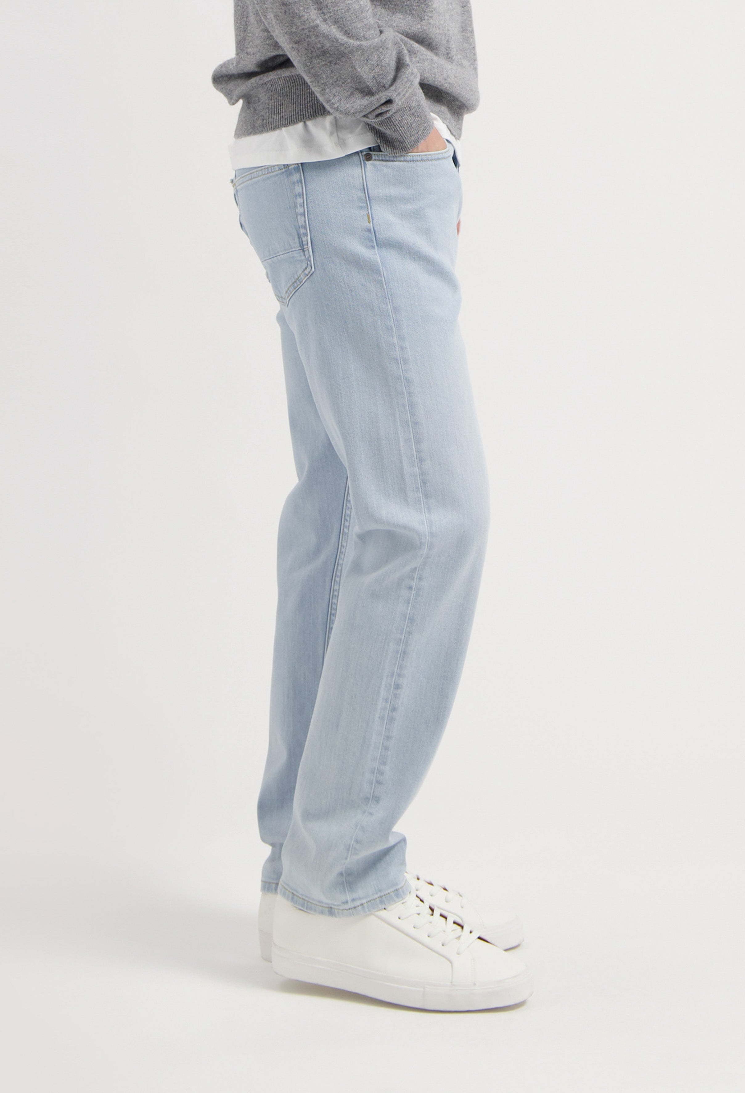 Sustainable MUD Jeans in gray organic cotton, offering a modern fit, paired with black sneakers for a casual look.