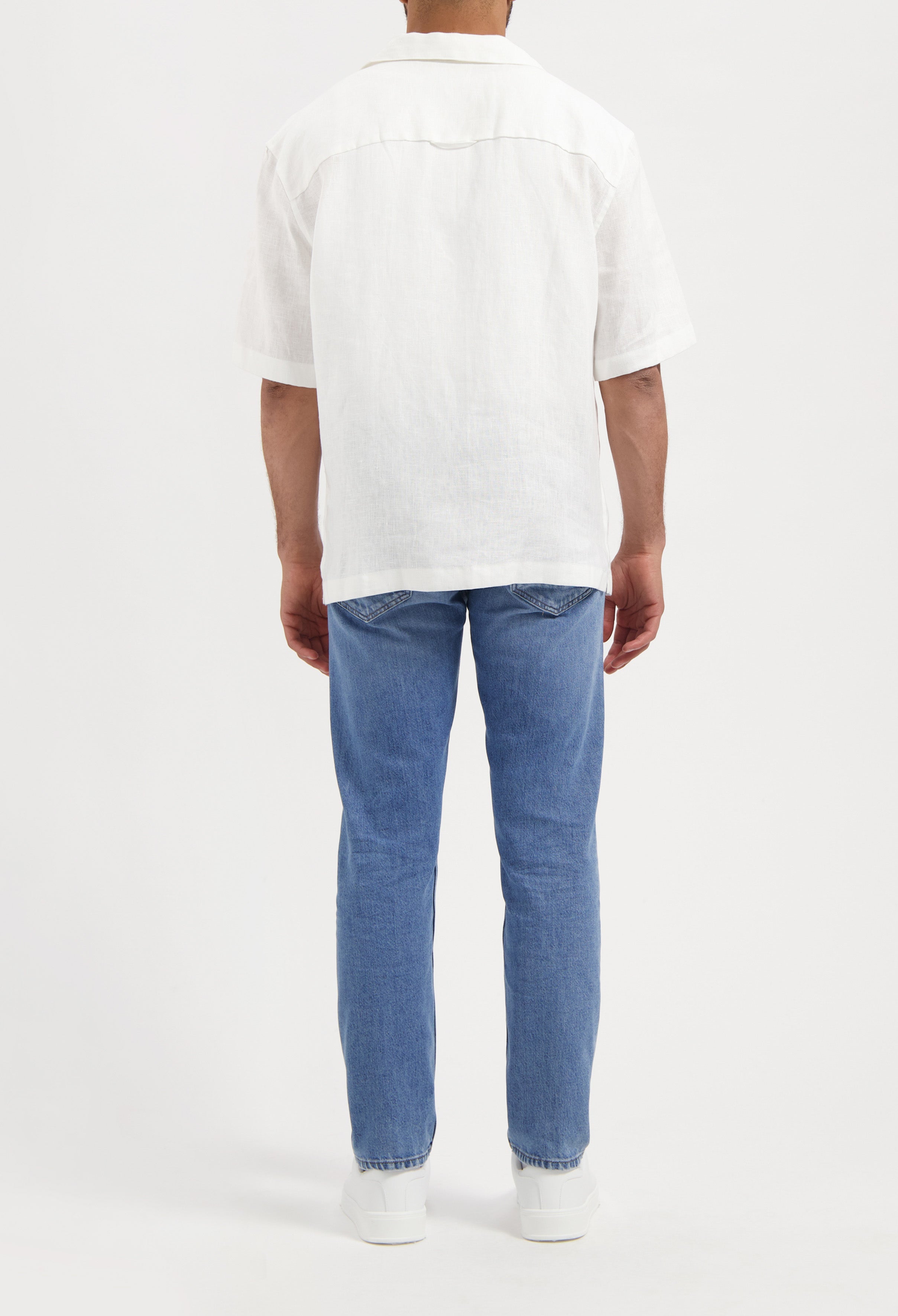 Sustainable MUD Jeans in light blue denim, crafted ethically from organic cotton, paired with a classic black t-shirt.