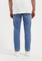 Sustainable MUD Jeans in light blue denim with a classic fit, promoting ethical fashion, paired with a black t-shirt.