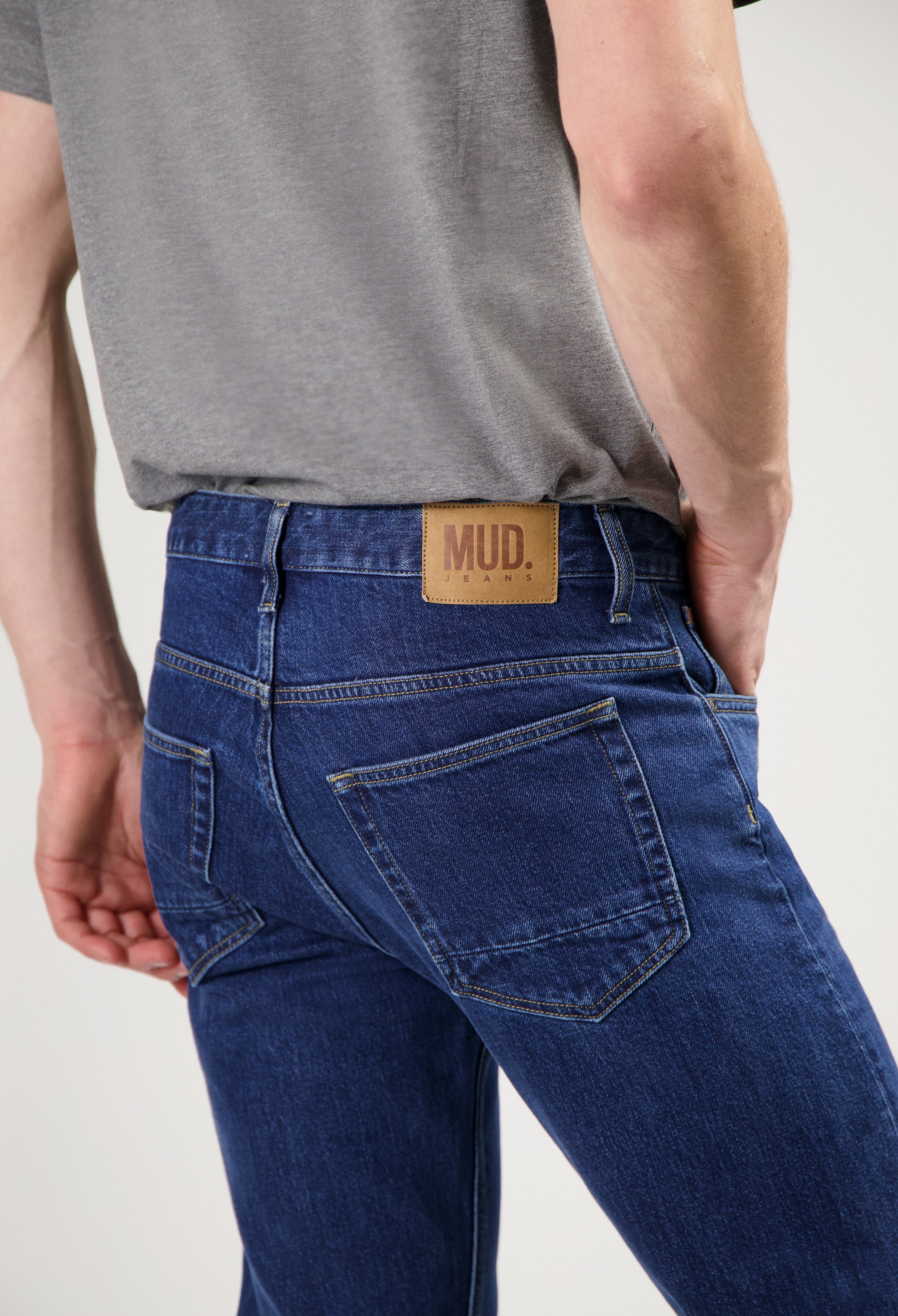 Model wearing Hank Mid Tapered jeans in medium stone, made from sustainable organic and recycled cotton, offering a tapered fit.