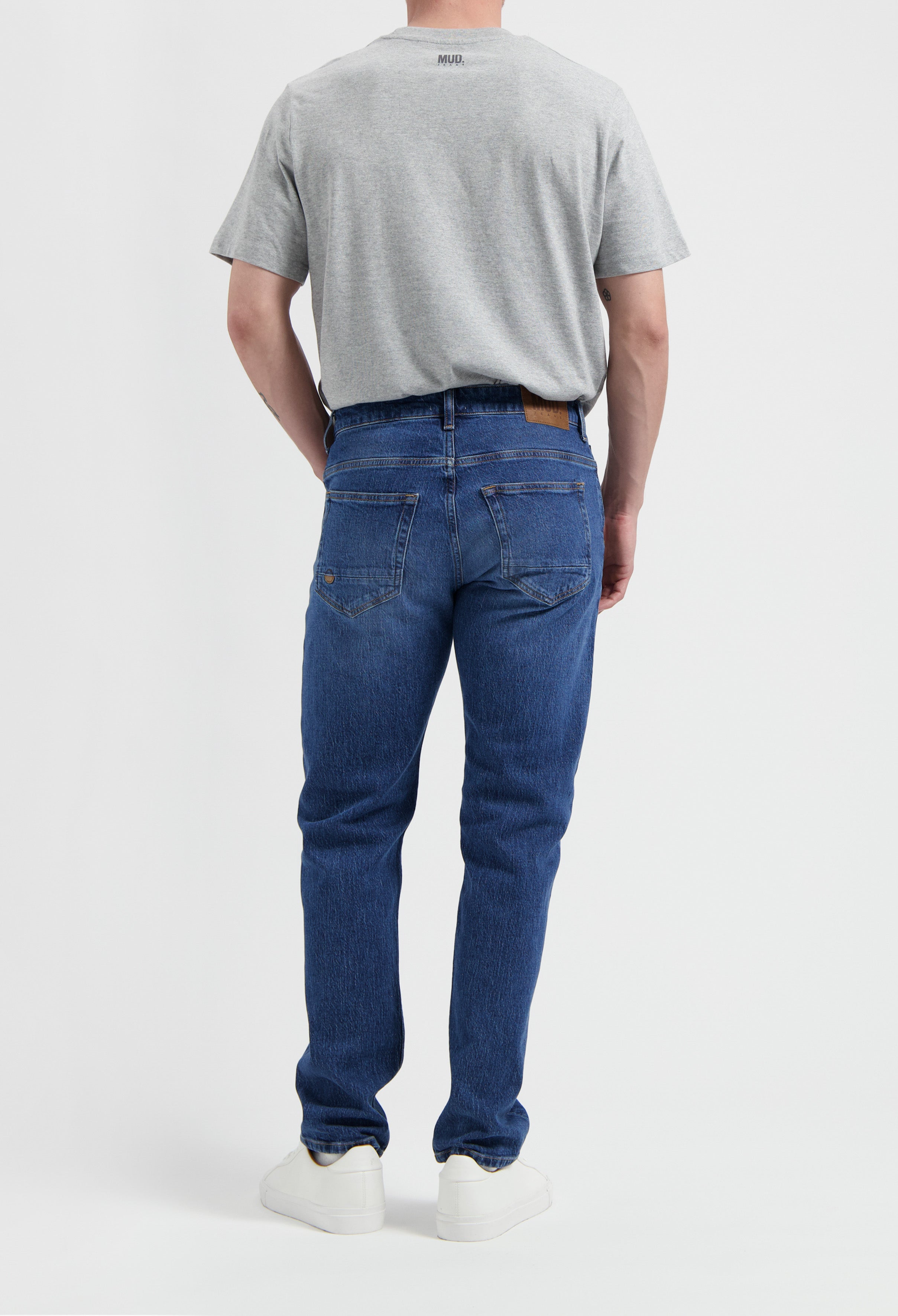 Sustainable MUD Jeans in dark blue denim, crafted ethically from organic cotton, paired with a simple white t-shirt.