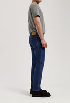 Model wearing Hank Mid Tapered jeans in medium stone, made from sustainable organic and recycled cotton, offering a tapered fit.