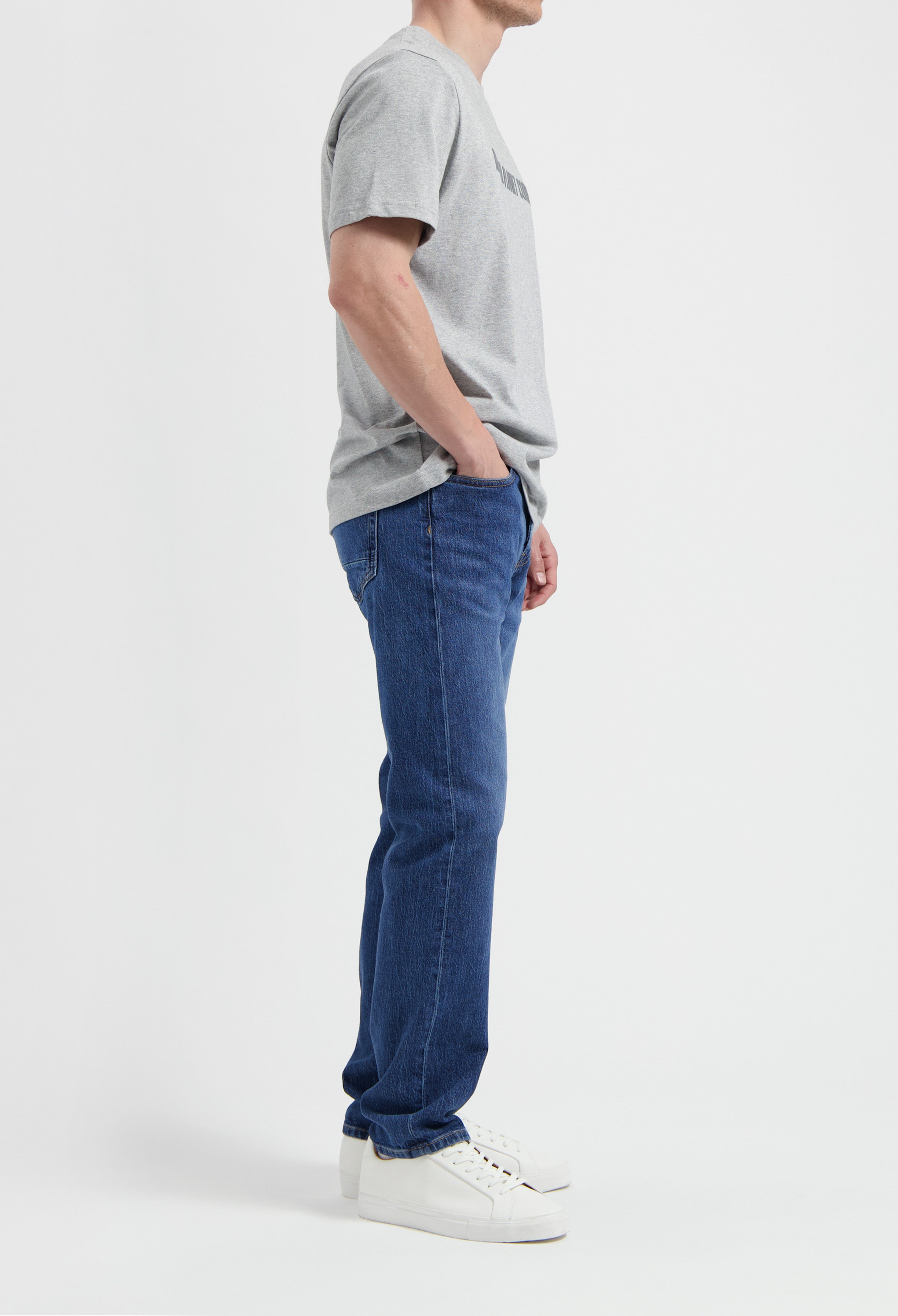 Sustainable MUD Jeans in deep blue denim paired with a classic fit, showcasing ethical fashion with a gray sweater.