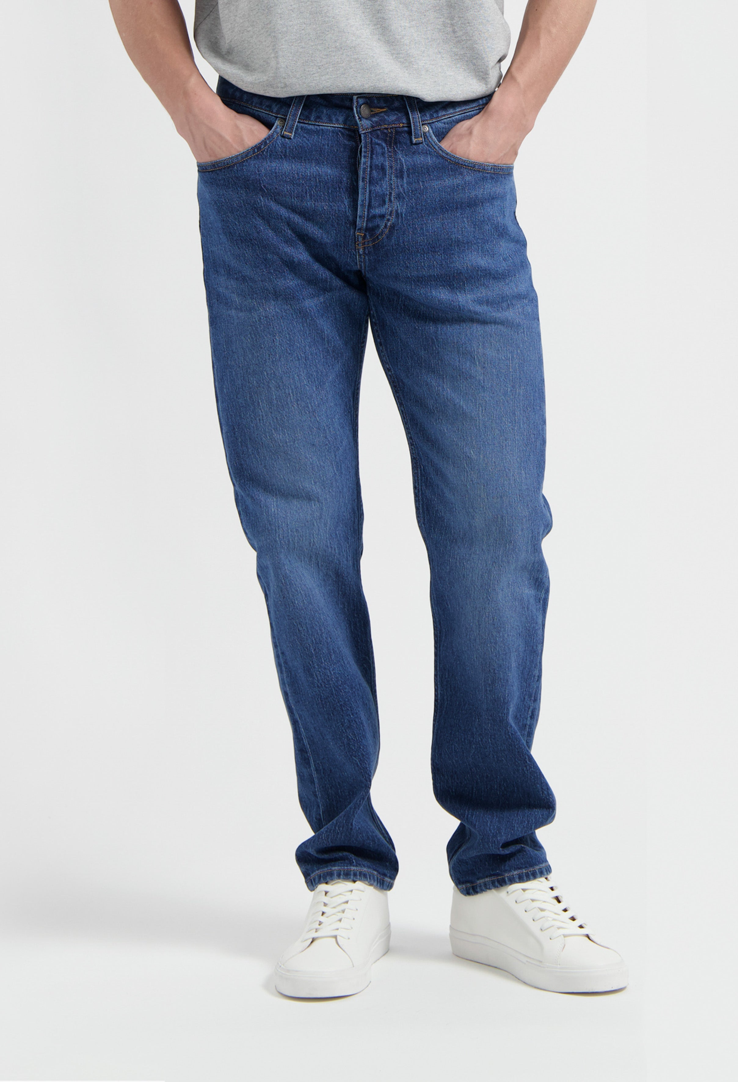 Sustainable MUD Jeans in dark blue denim, ethically made for casual wear, paired with a white t-shirt and sneakers.