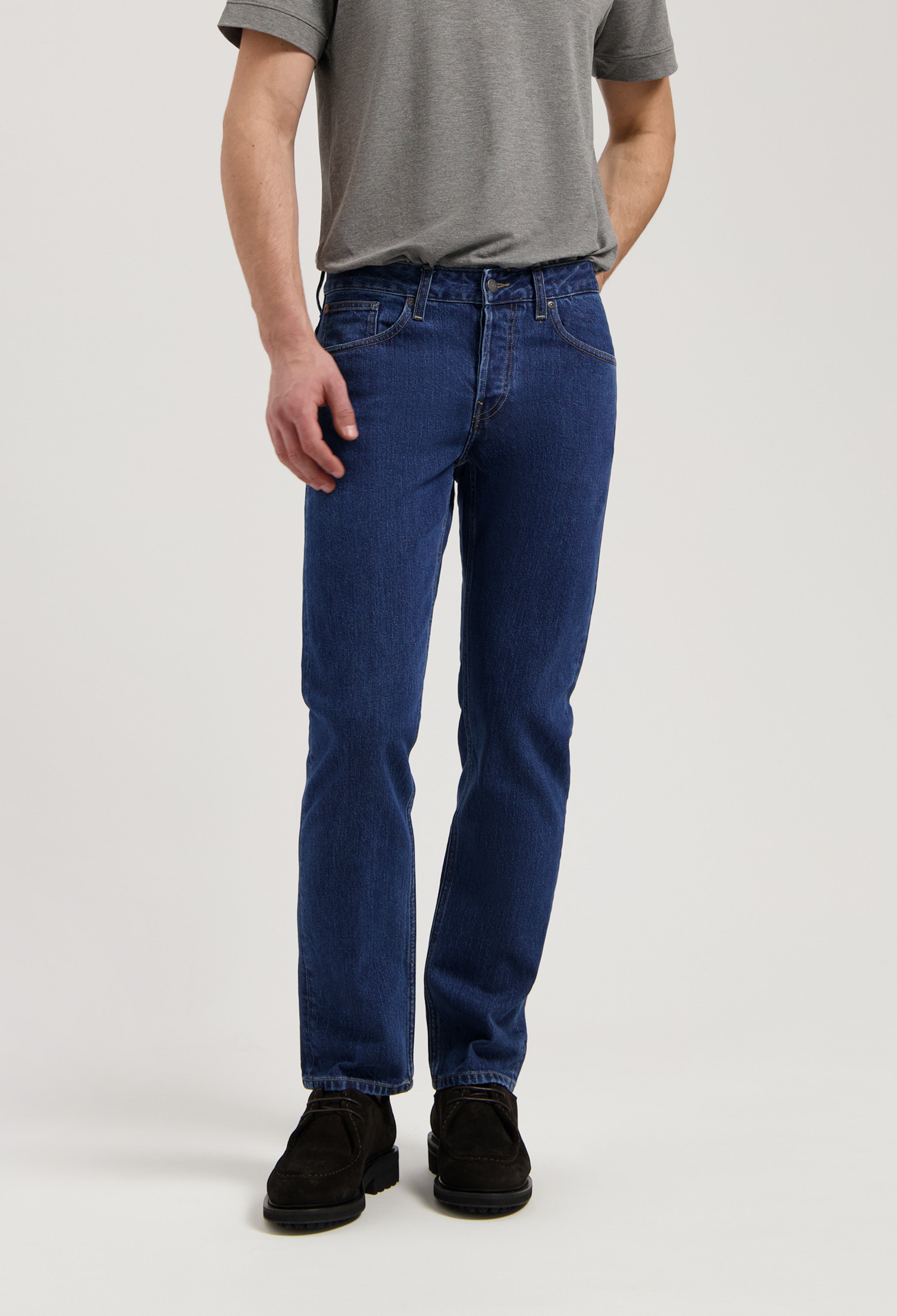 Model wearing Hank Mid Tapered jeans in medium stone, made from sustainable organic and recycled cotton, offering a tapered fit.