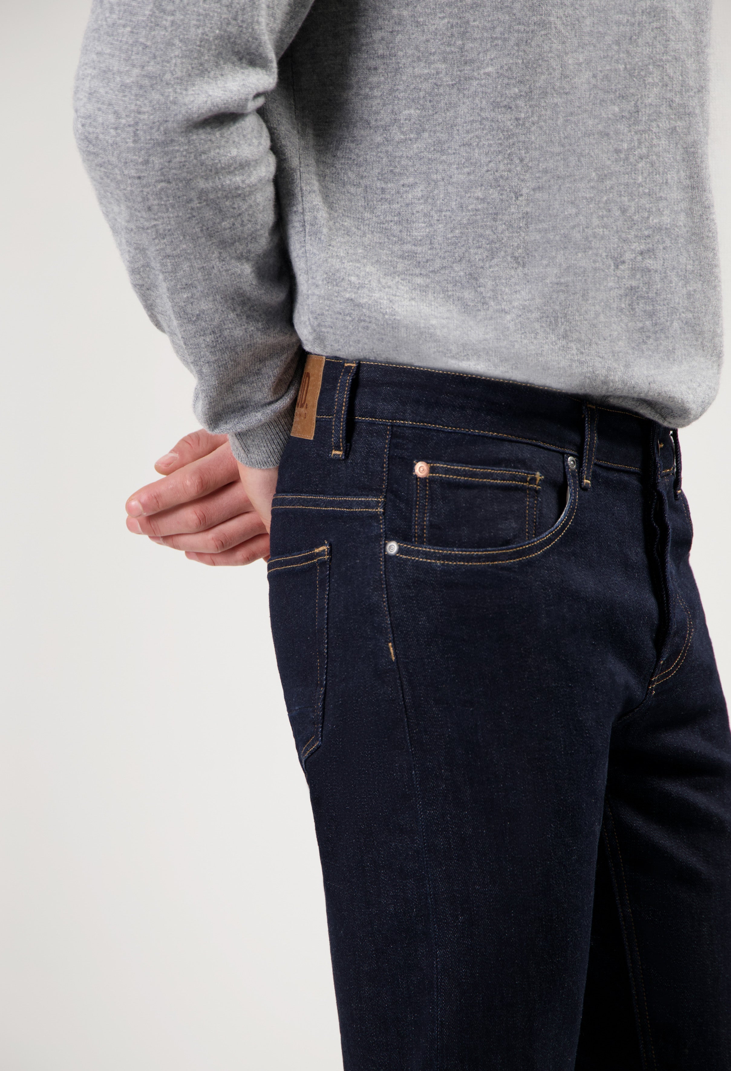 Sustainable MUD Jeans in dark blue denim, crafted ethically, paired with a soft gray sweater showcasing modern style.