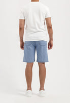 Sustainable MUD Jeans in dark denim with a slim fit, paired with a casual gray sweater and white sneakers.