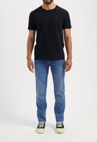 Sustainable MUD Jeans in light blue denim, ethically made, viewed from back, paired with a black shirt.
