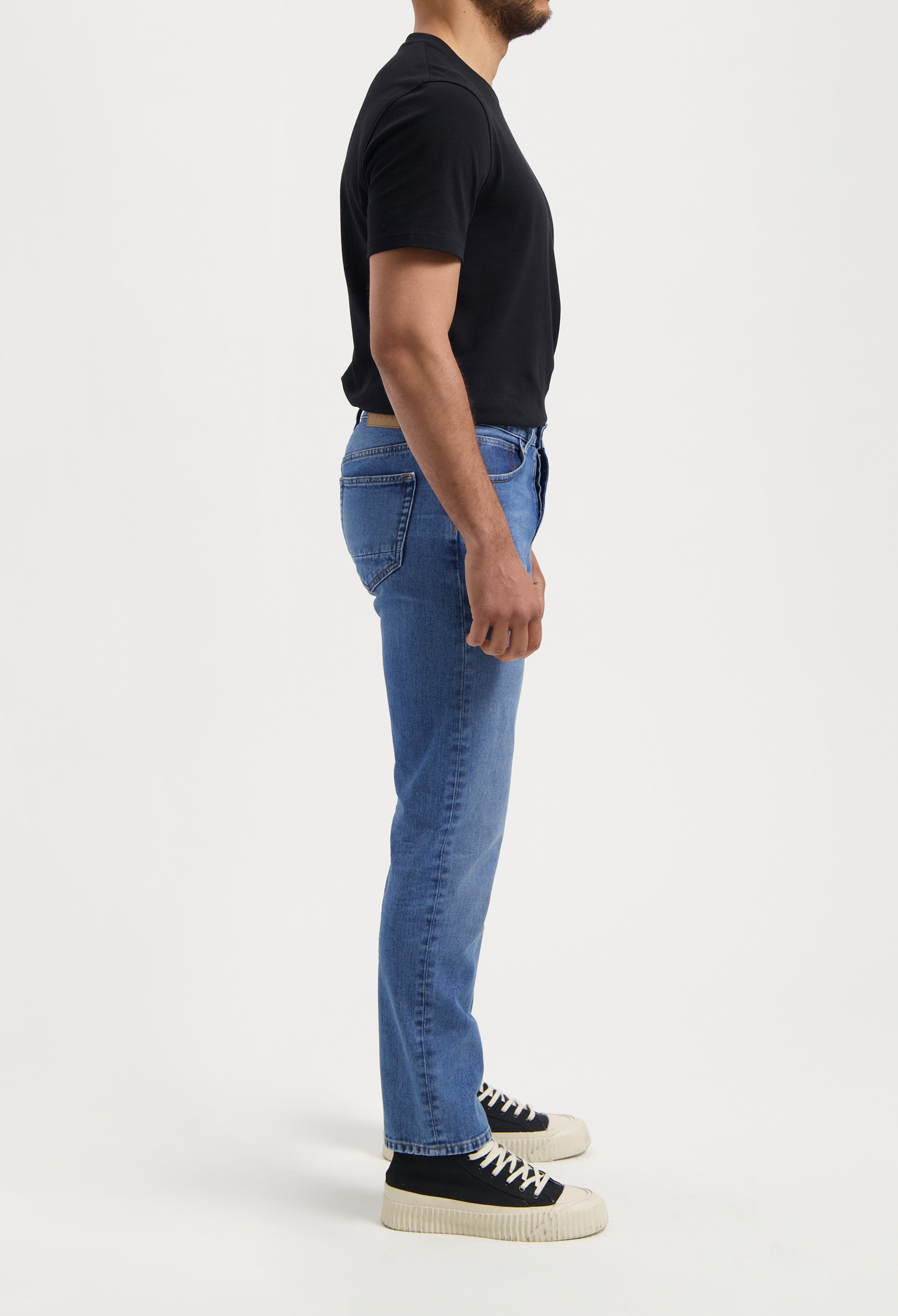 Light blue MUD Jeans in sustainable denim, featuring a classic fit and leather brand patch, styled with a black shirt.
