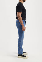 Light blue MUD Jeans in sustainable denim, featuring a classic fit and leather brand patch, styled with a black shirt.