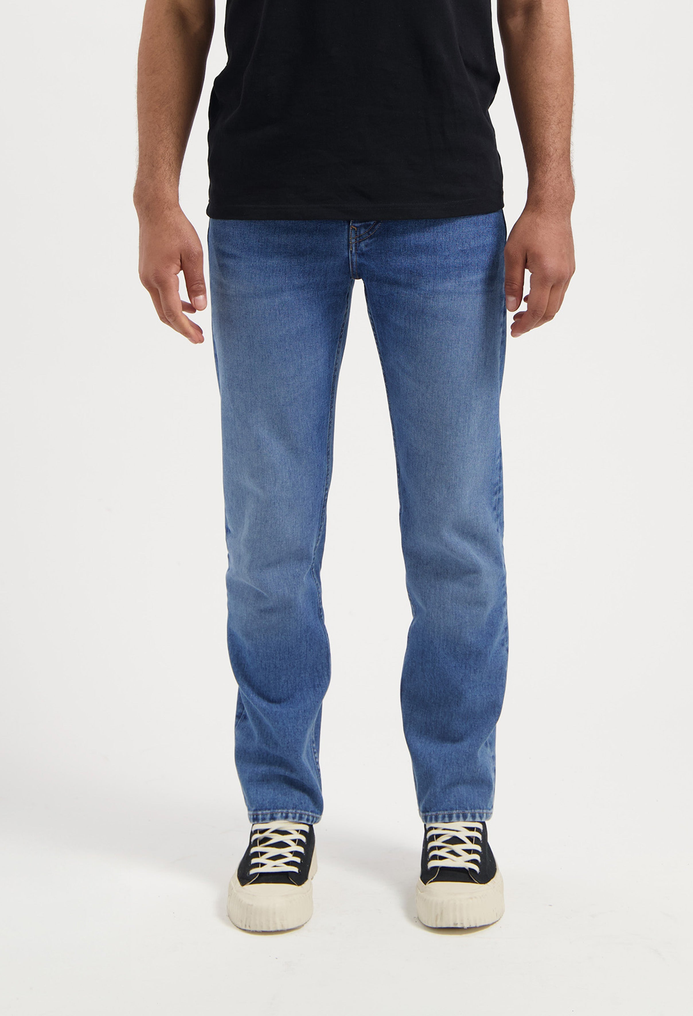 Sustainable black MUD Jeans made from organic cotton, featuring a relaxed fit and paired with a white tee.