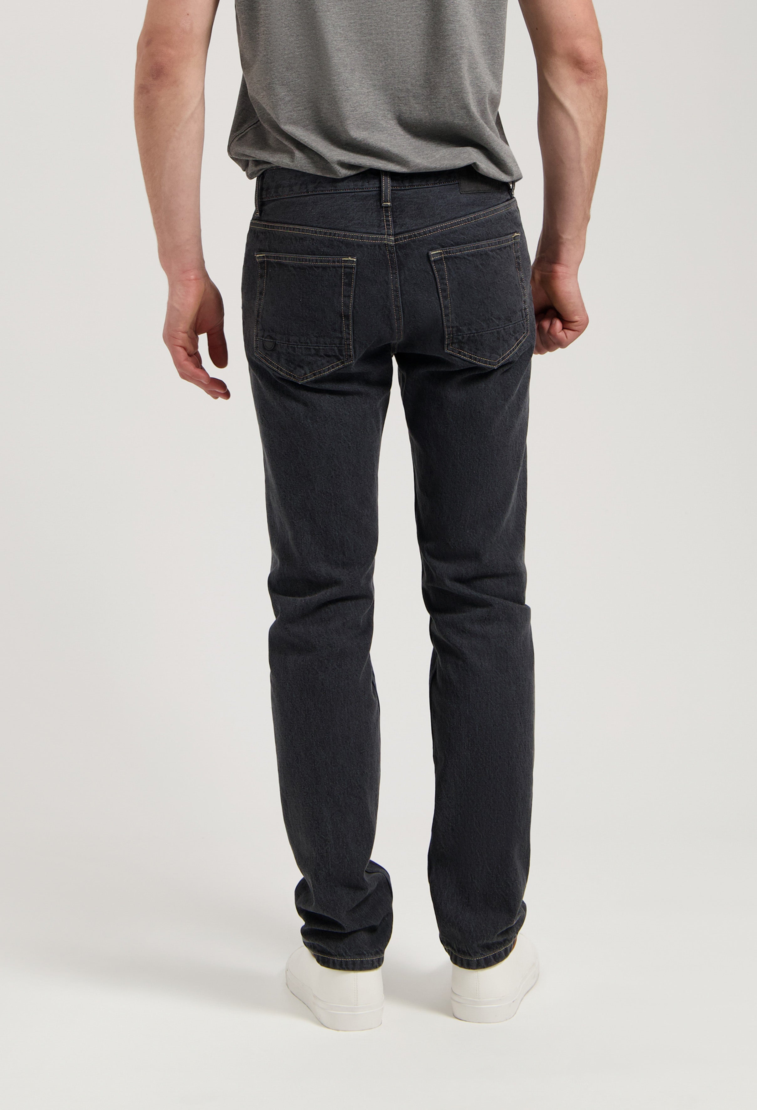 Sustainable MUD Jeans in dark denim, ethical fashion with slim fit, paired with an eco-friendly cream sweater.
