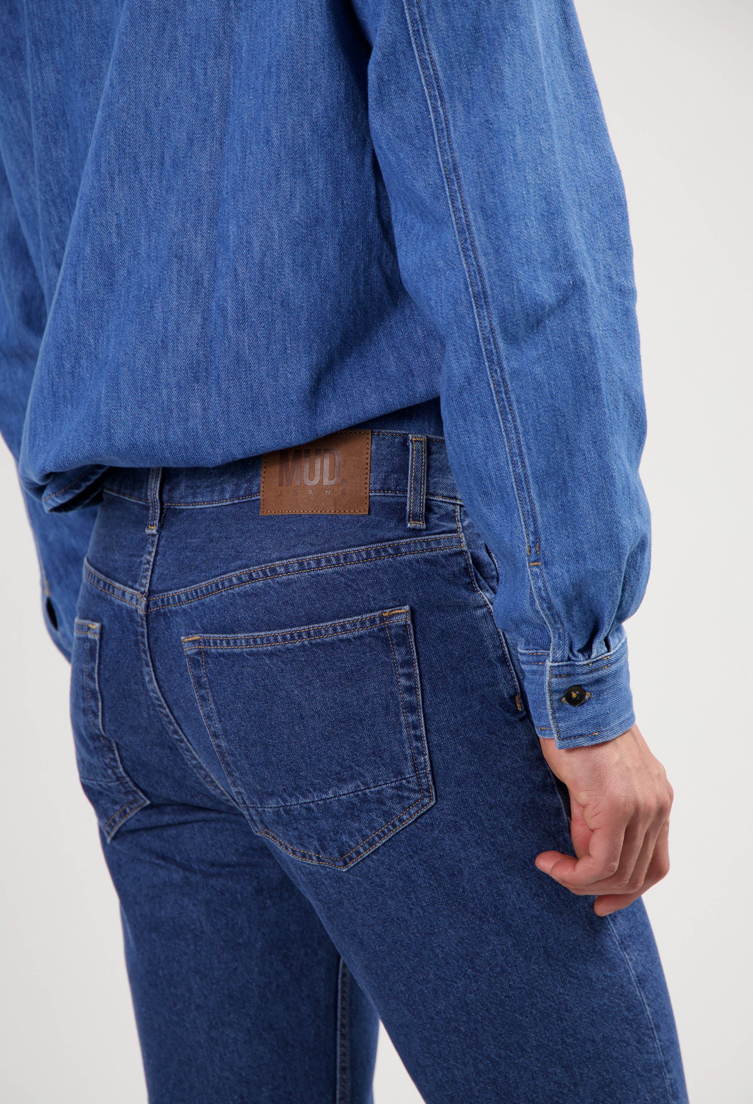 Sustainable MUD Jeans made from ethical denim, featuring dark blue material, paired with a casual white shirt.