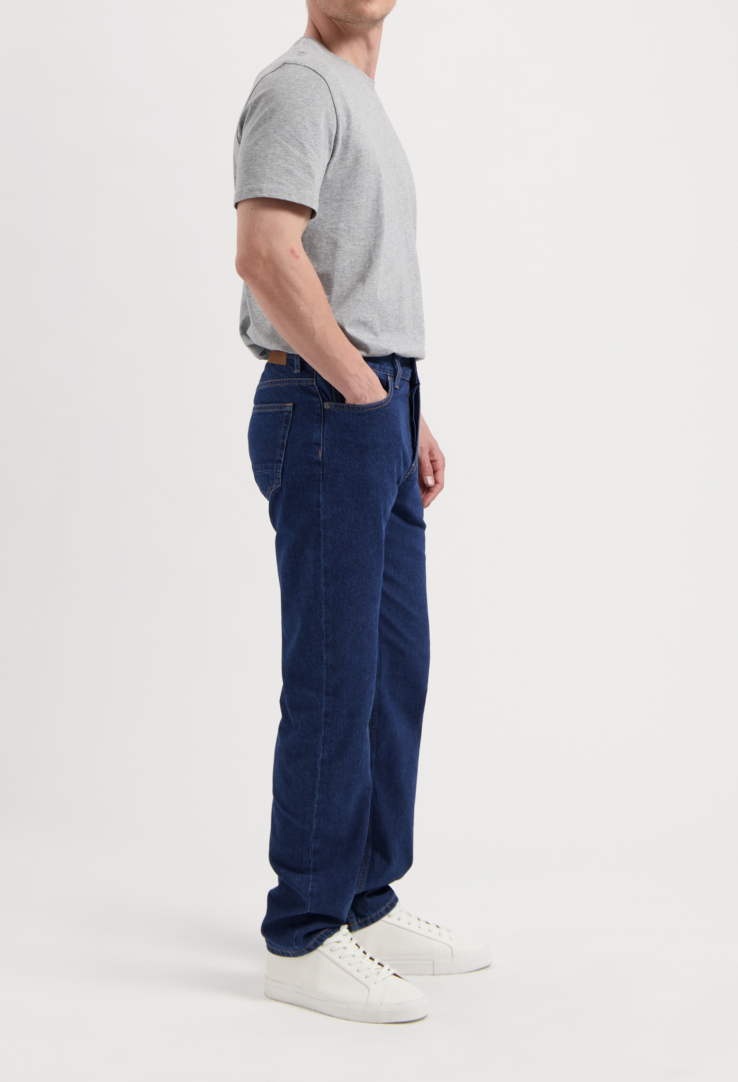 Sustainable MUD Jeans in dark denim, crafted from eco-friendly materials, paired with a white tee and brown sweater.