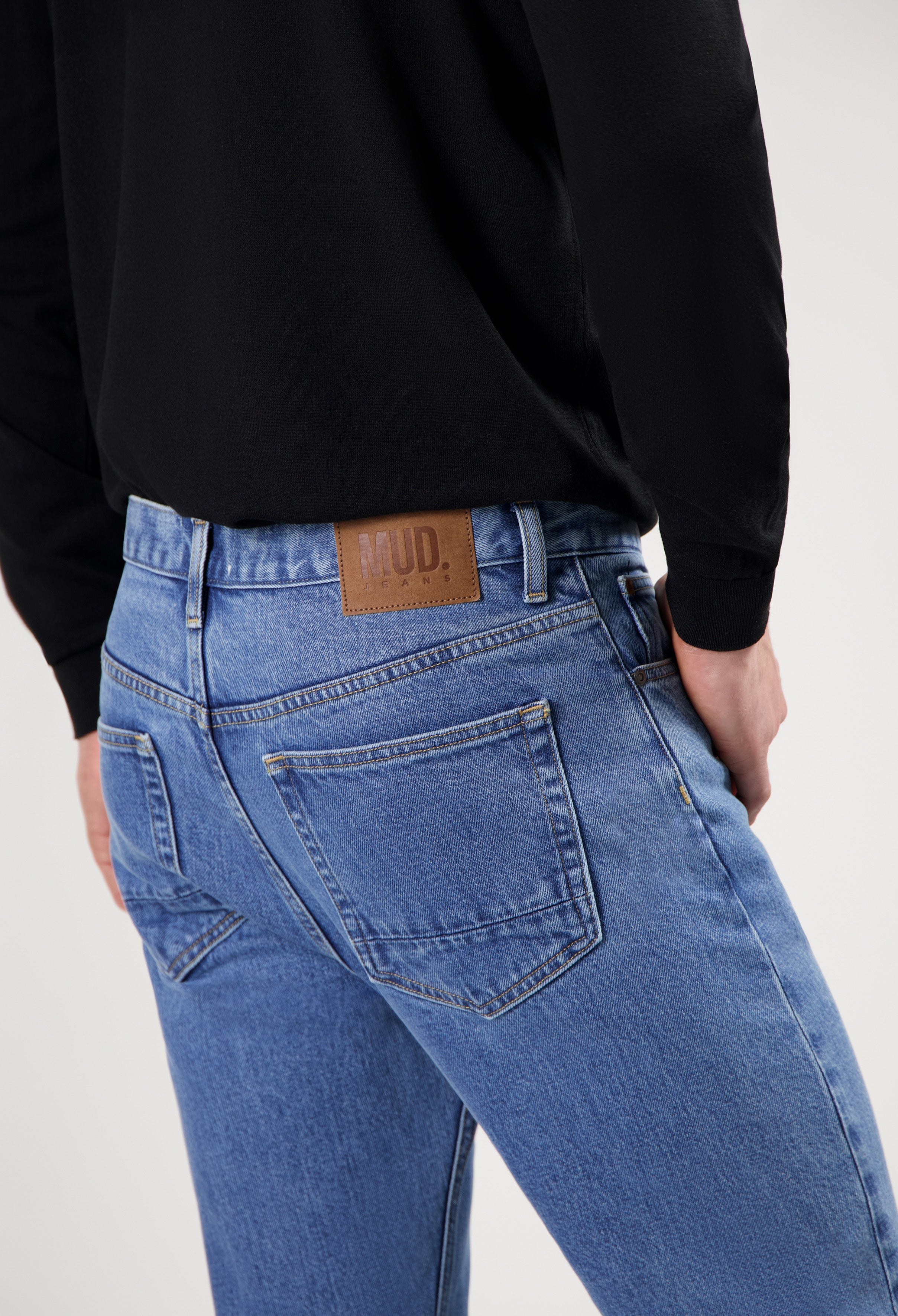 Sustainable MUD Jeans in blue denim, featuring a classic cut and ethical design, worn with a black top.