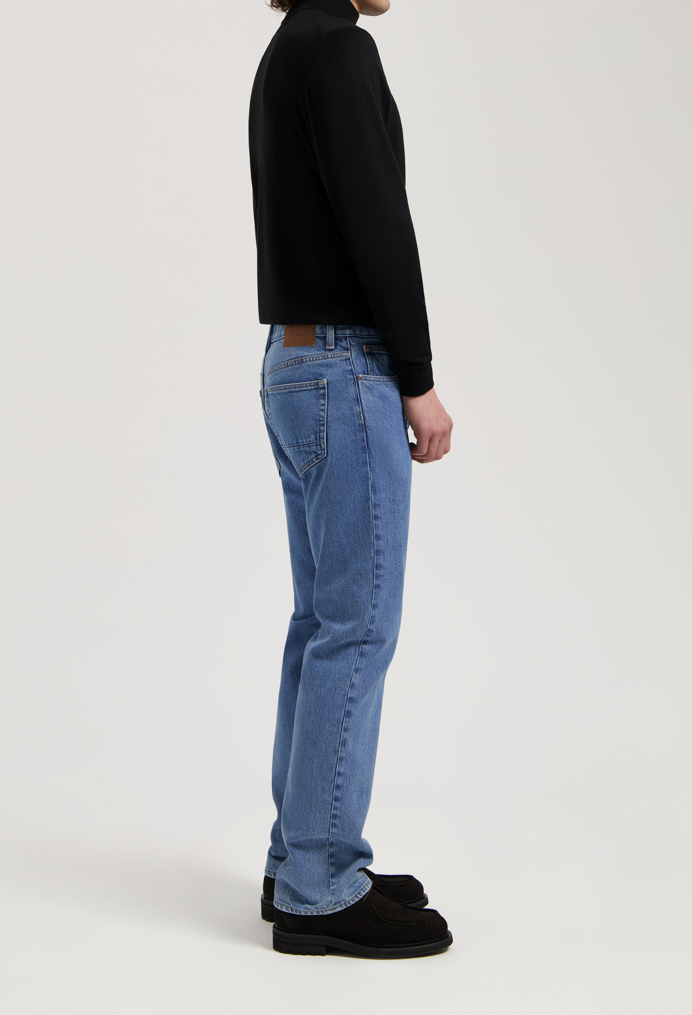 Sustainable MUD Jeans crafted from light blue denim, showcasing a straight fit, paired with a sleek black top.