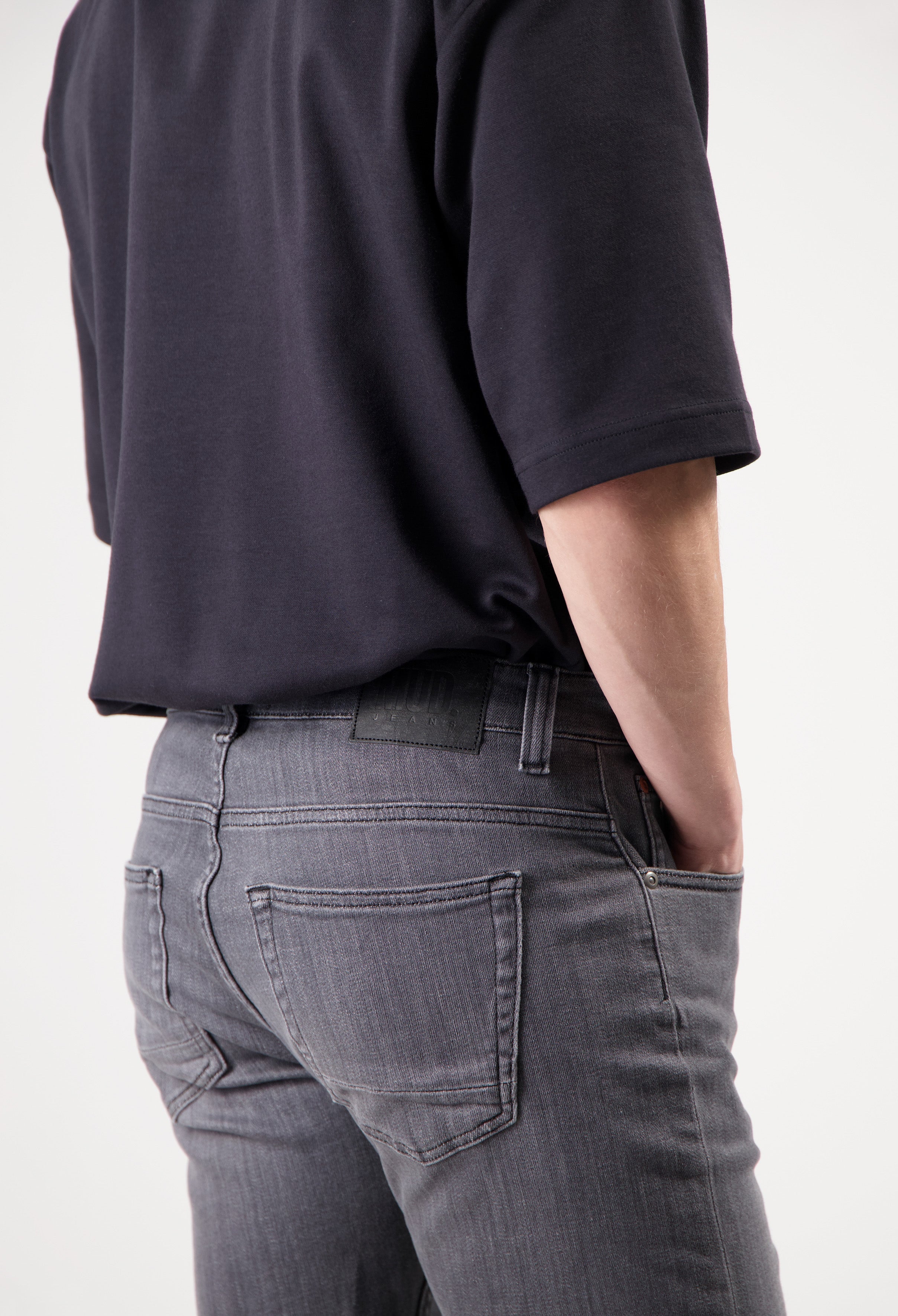 Sustainable MUD Jeans in dark blue denim, crafted ethically, paired with a casual gray T-shirt and white sneakers.