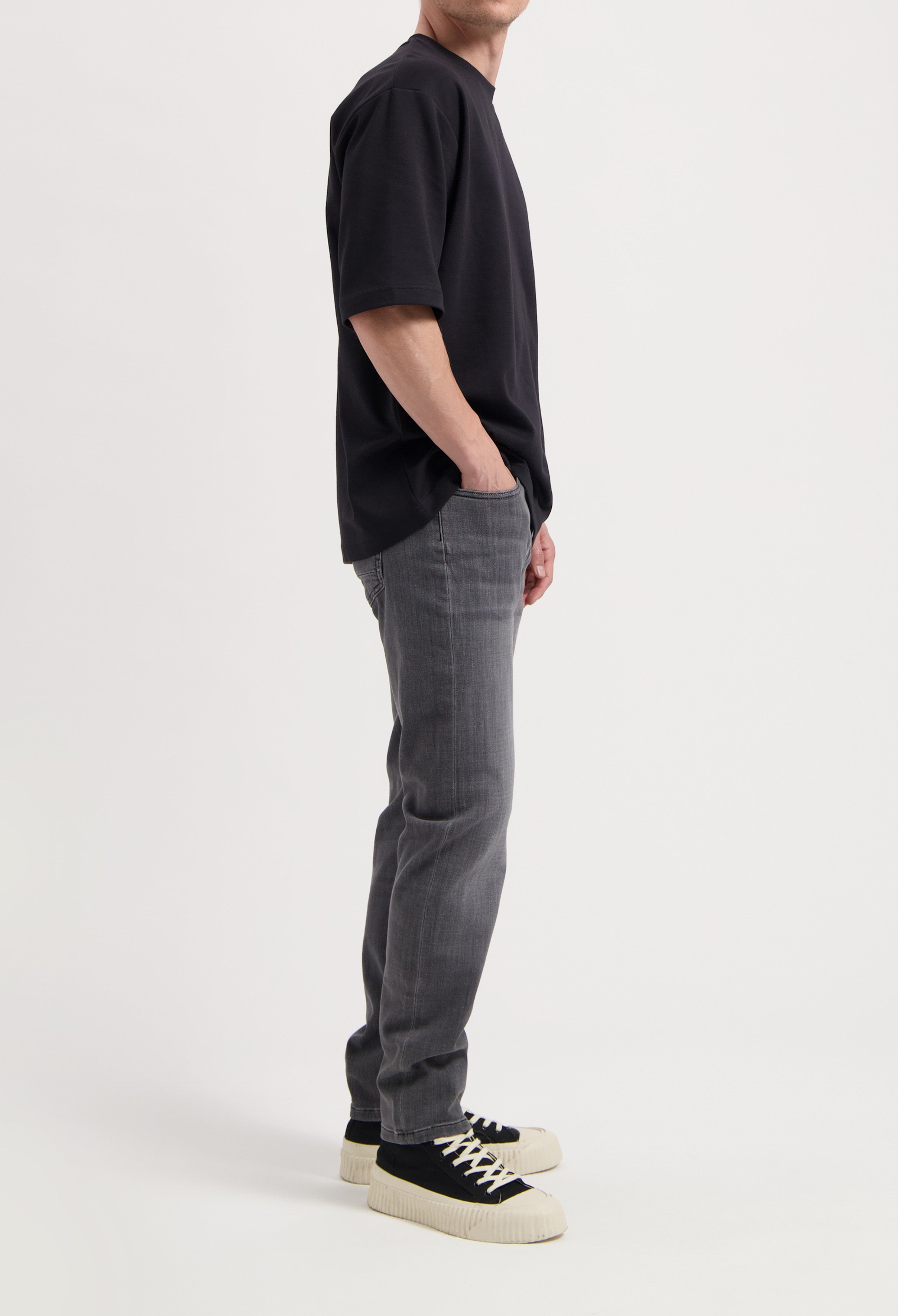 Sustainable MUD Jeans crafted from organic cotton, dark blue denim in slim fit, paired with a casual gray t-shirt.