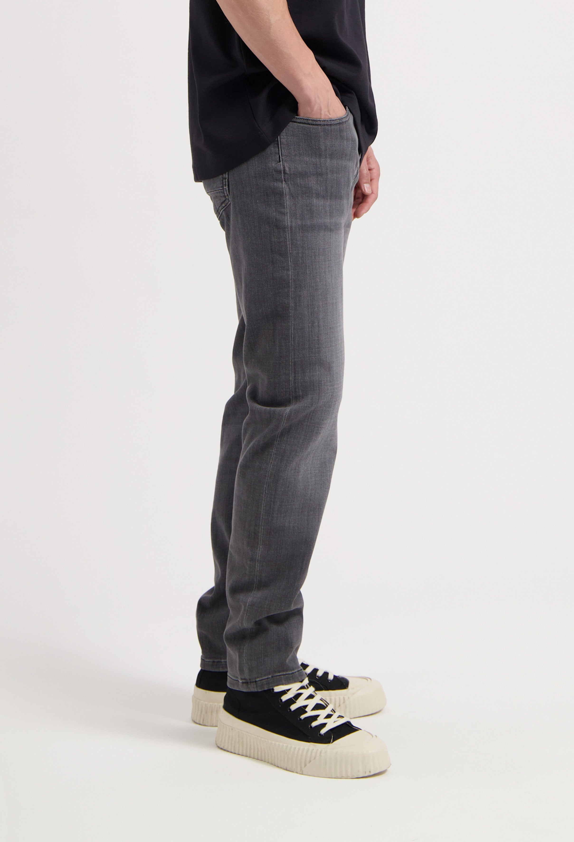 Sustainable MUD Jeans in light blue denim, crafted ethically, featuring a classic fit, paired with a white top.