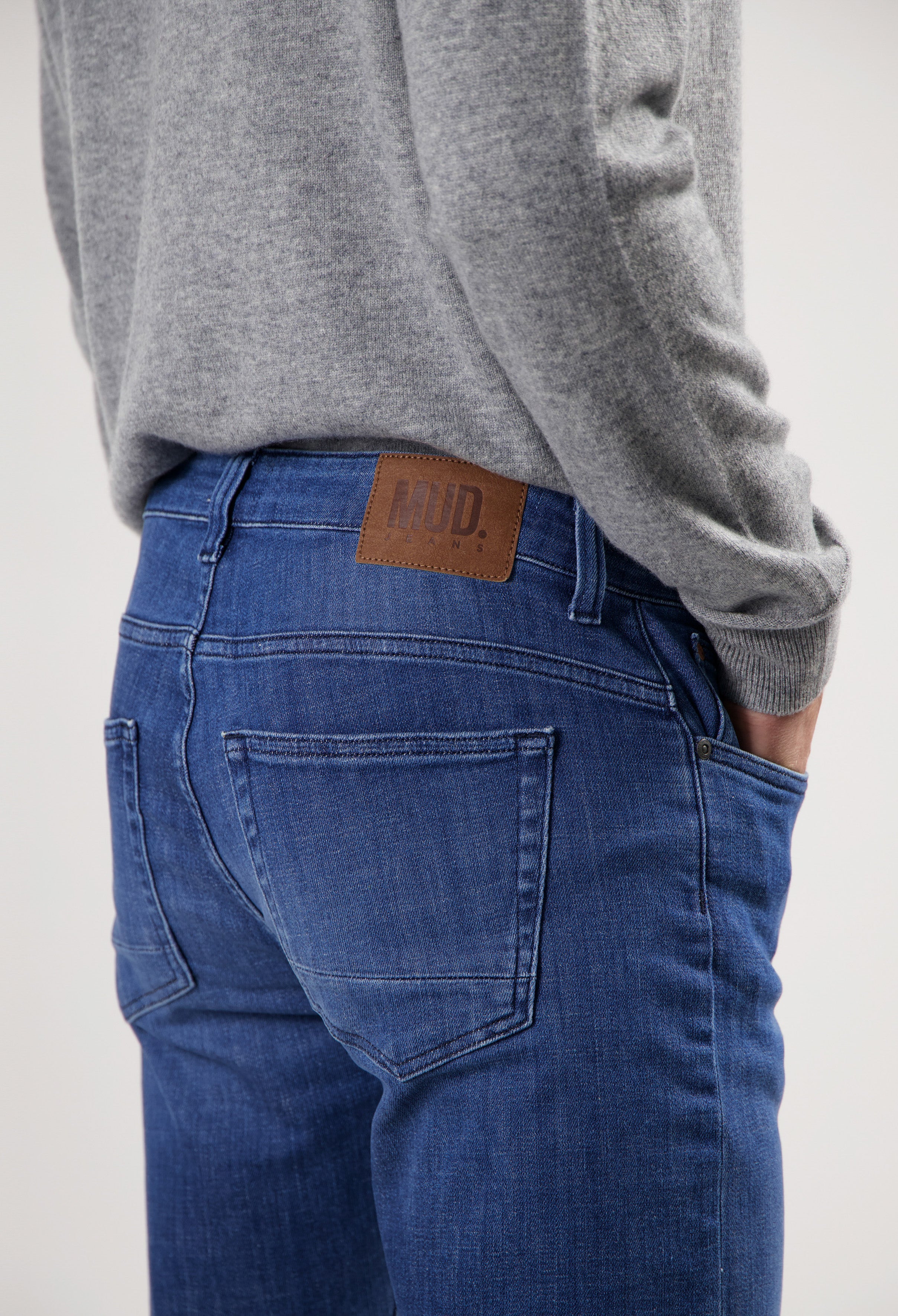Sustainable MUD Jeans in dark blue denim with a classic fit, styled with a gray sweater for an ethical fashion look.