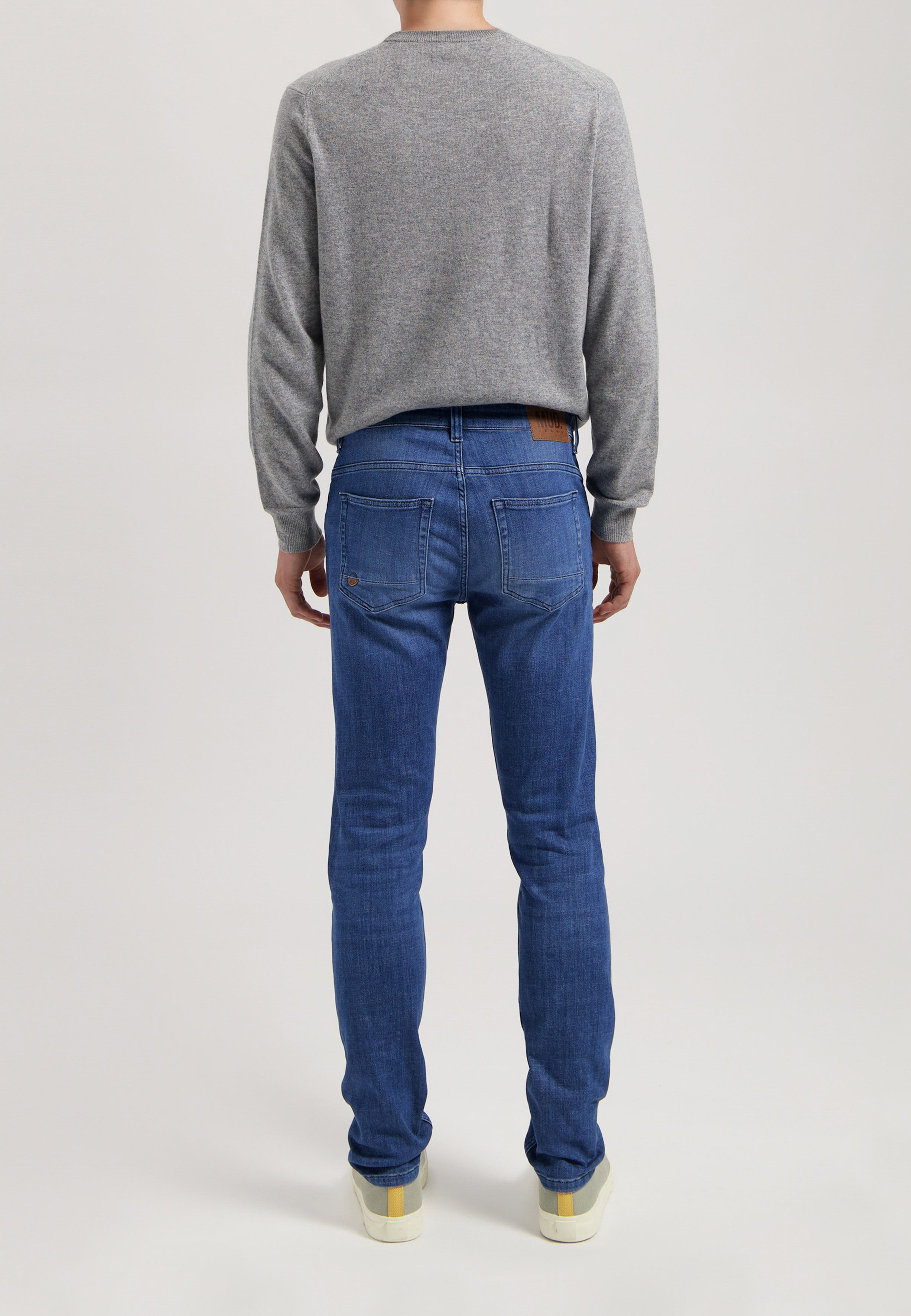 Eco-friendly MUD Jeans in deep blue denim, paired with a gray sweater, embodying sustainable fashion and ethical style.