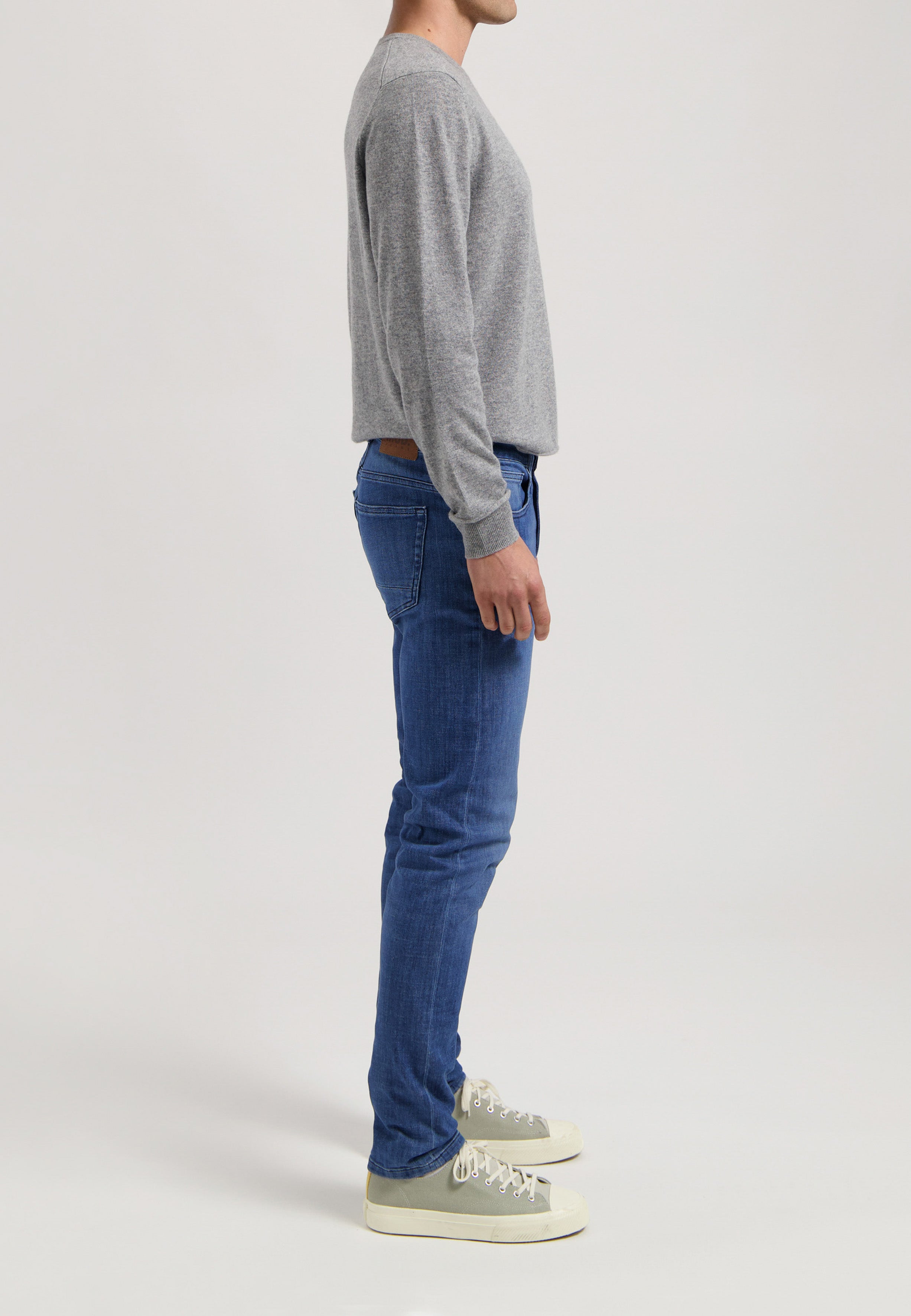 Sustainable MUD Jeans in dark blue denim featuring classic fit, paired with a soft gray sweater for ethical style.