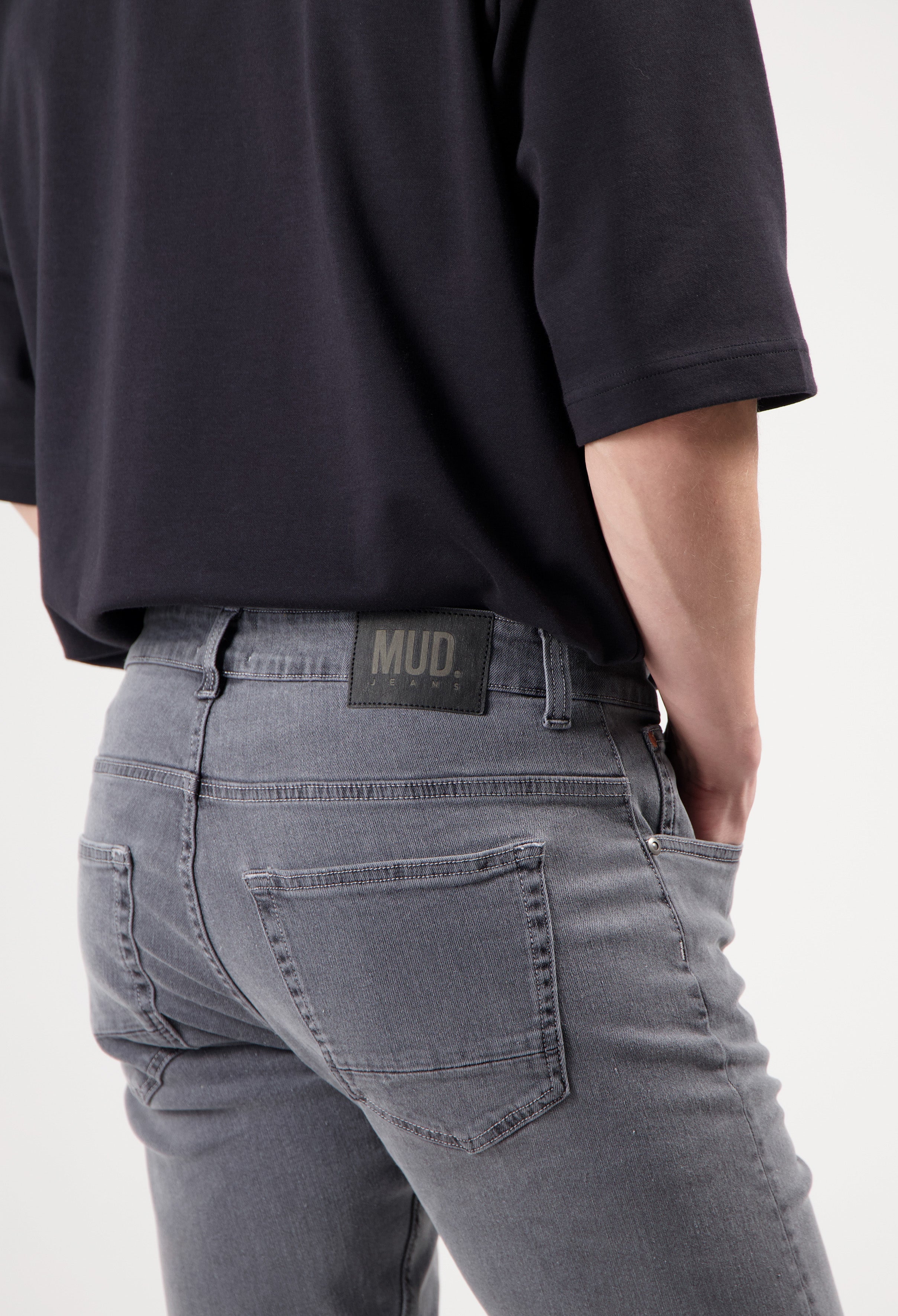 Sustainable Mud Jeans in dark gray, classic fit, made from ethical materials, paired with a white long-sleeve shirt.