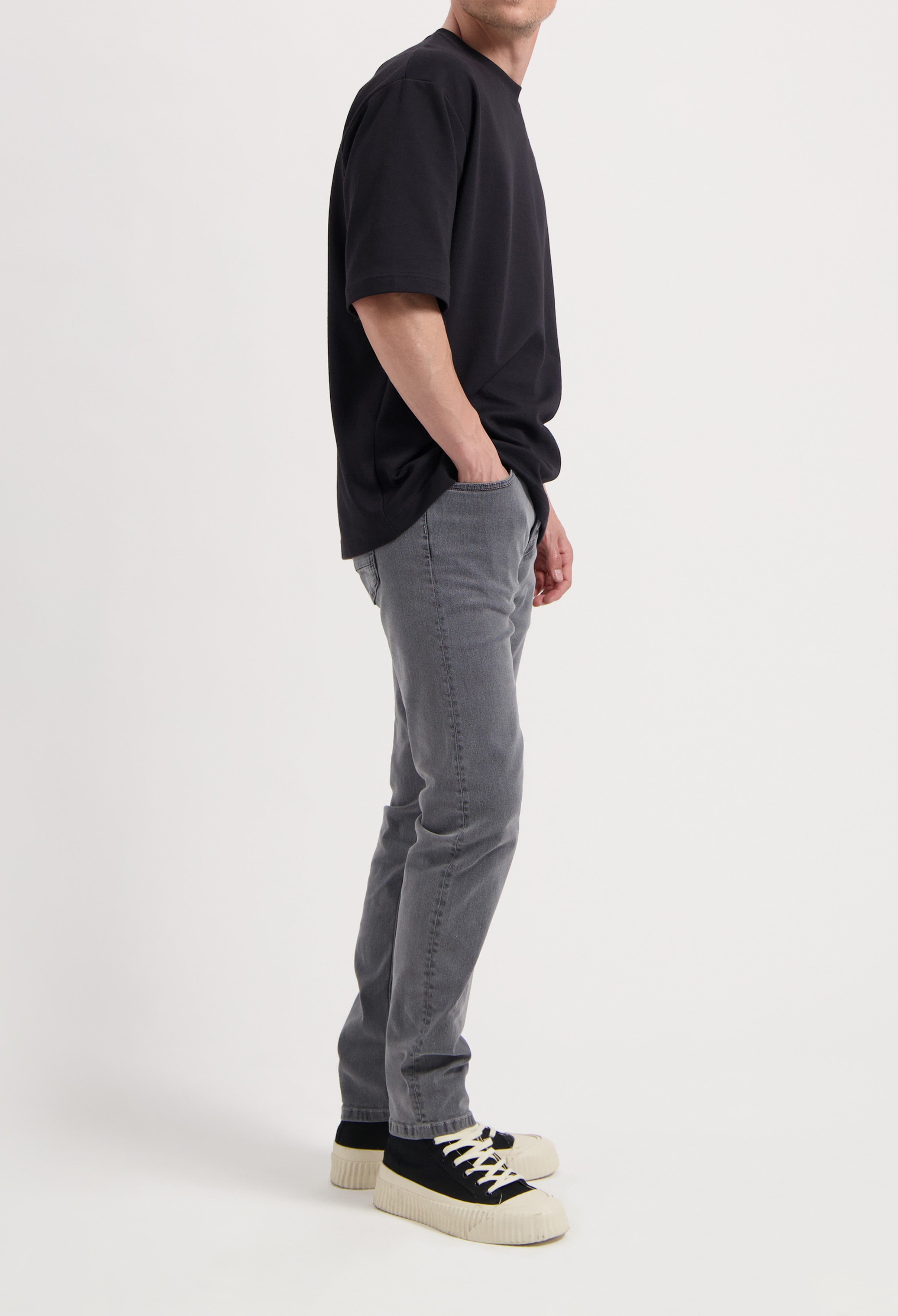 Sustainable MUD Jeans in light blue denim, crafted ethically, paired with a white long-sleeve shirt.