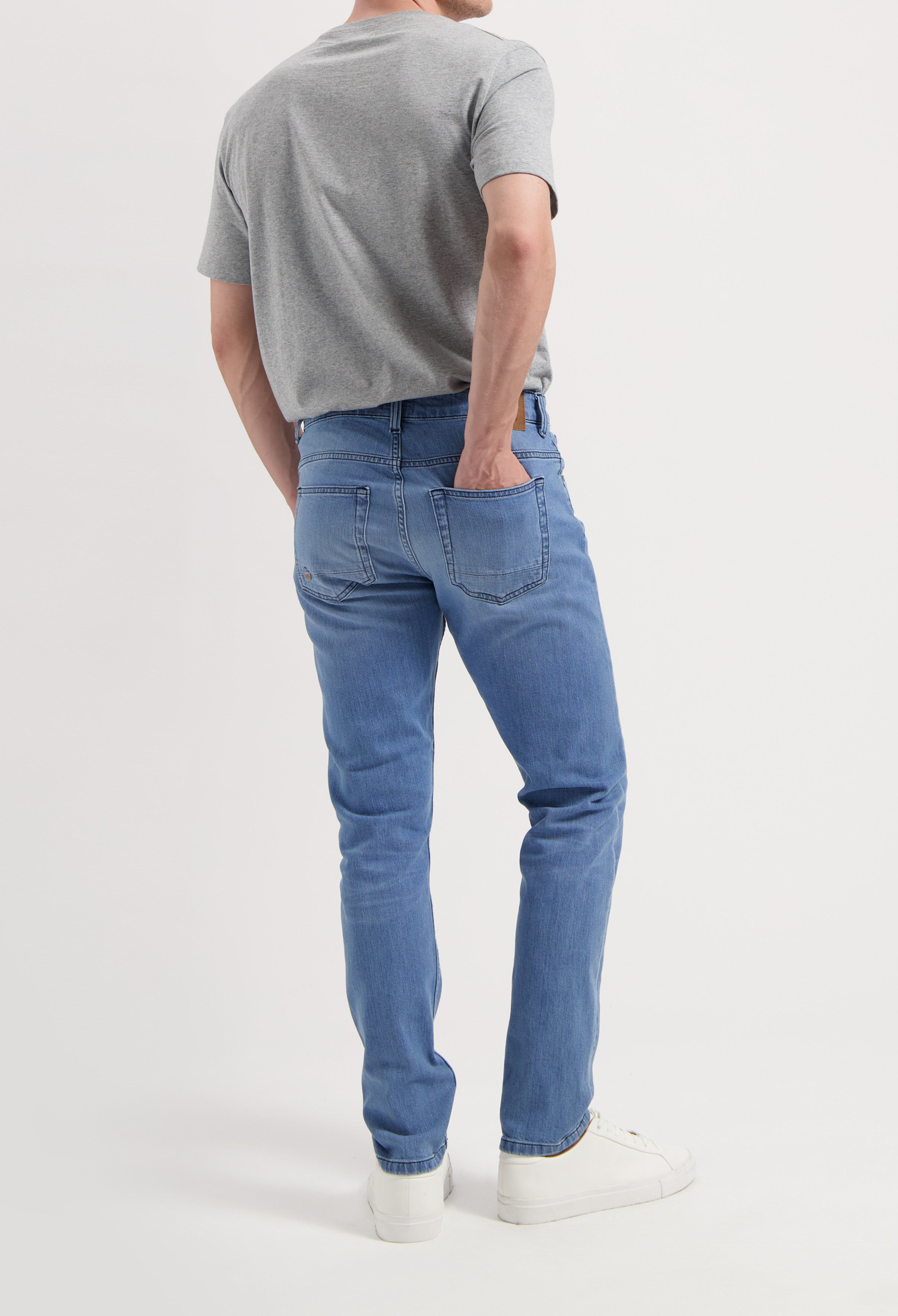 Sustainable MUD Jeans in deep blue denim, ethically made, paired with a simple white t-shirt and white sneakers.