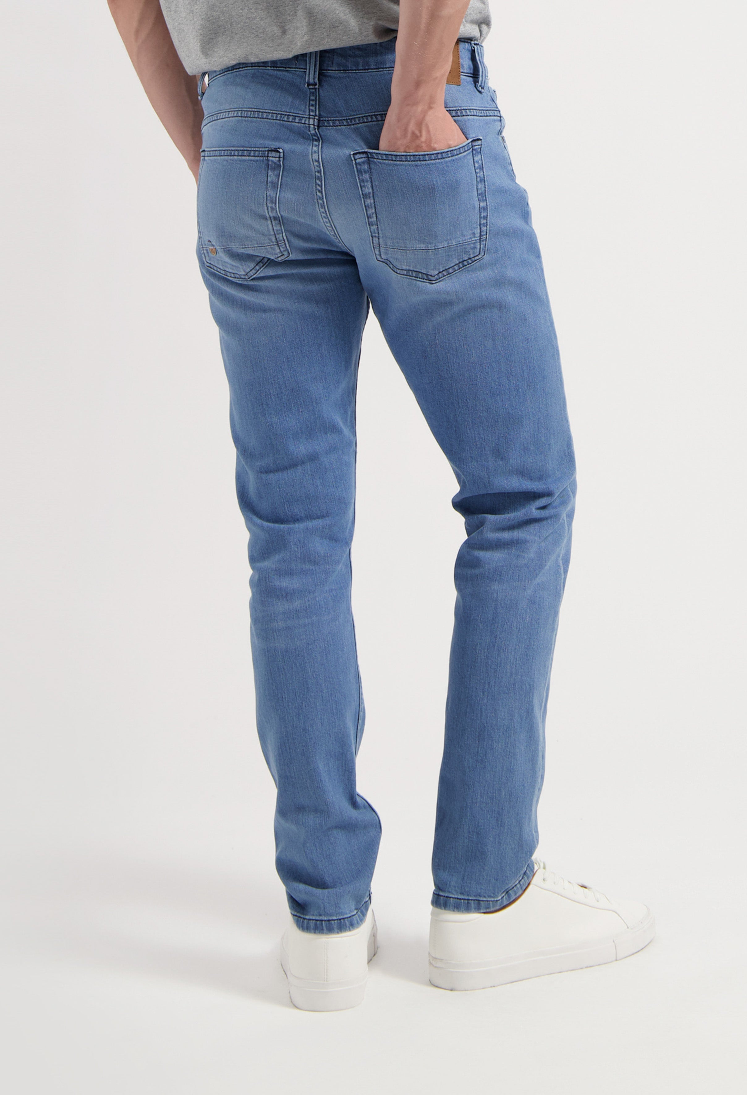 Sustainable MUD Jeans in dark blue denim, showcasing an ethical, relaxed fit, paired with white sneakers.