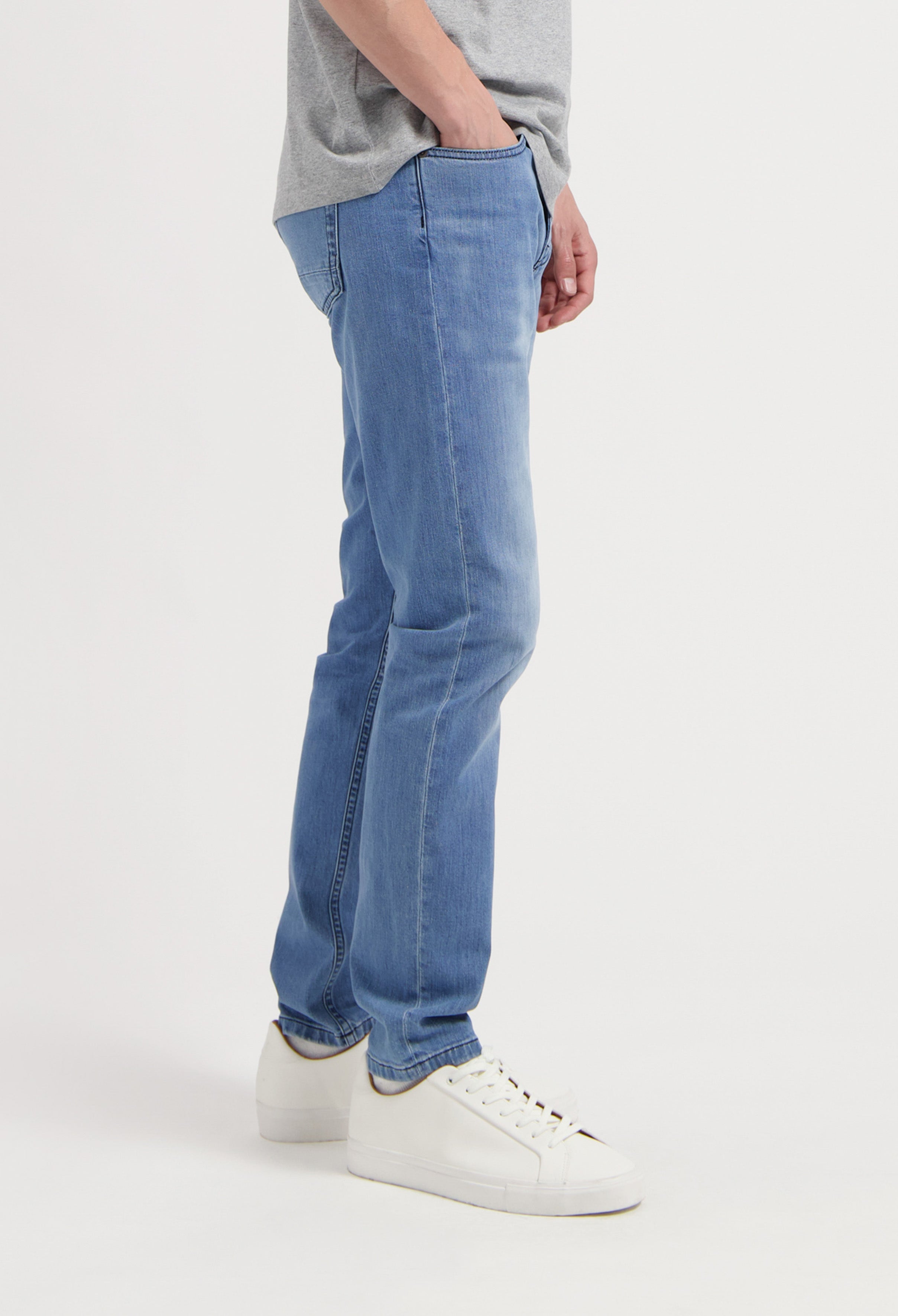 Sustainable MUD Jeans in dark wash denim, showcasing ethical style, paired with white sneakers and a casual look.