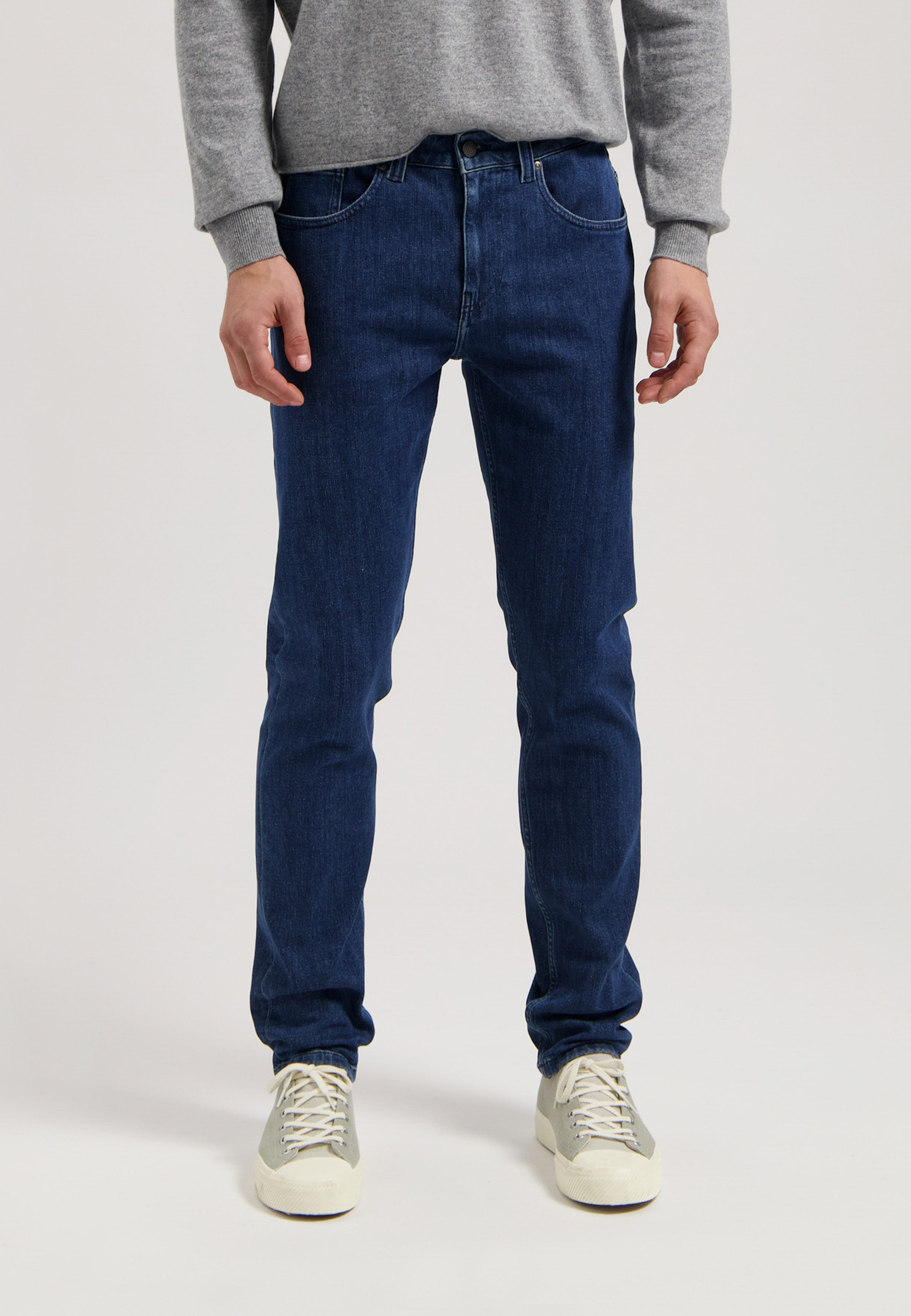 Sustainable MUD Jeans in dark denim, styled with white tops for an ethical fashion look, perfect for casual wear.