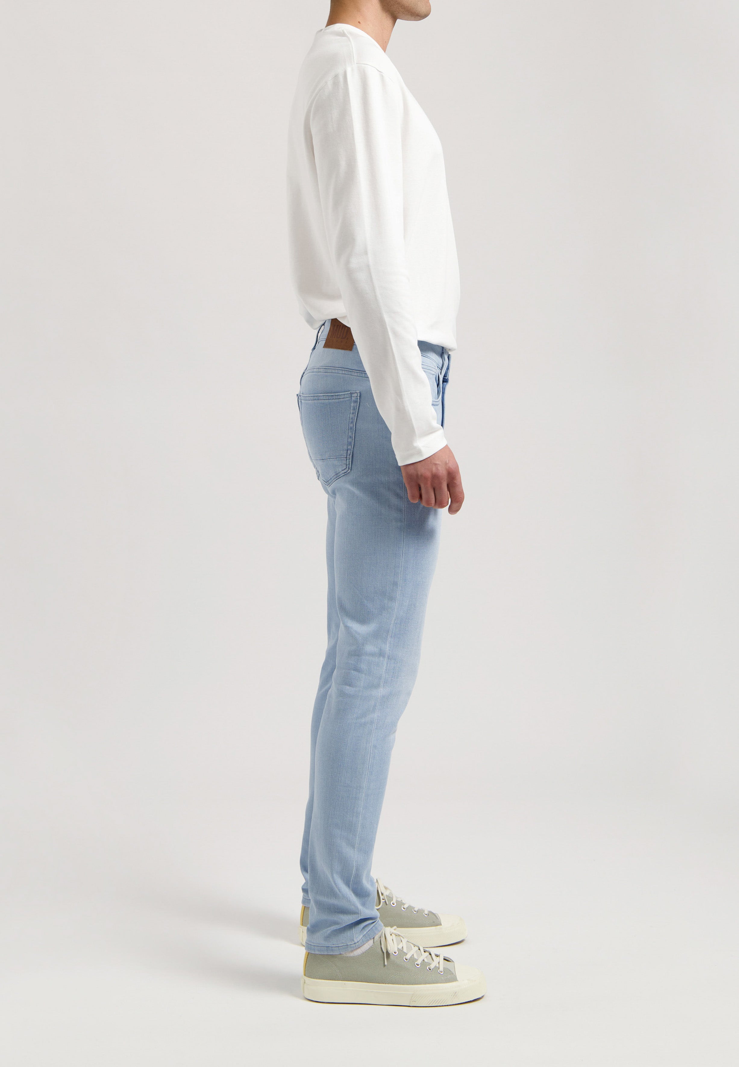 Sustainable MUD Jeans in classic fit with a dark jacket, designed for ethical fashion, paired with a casual white tee.