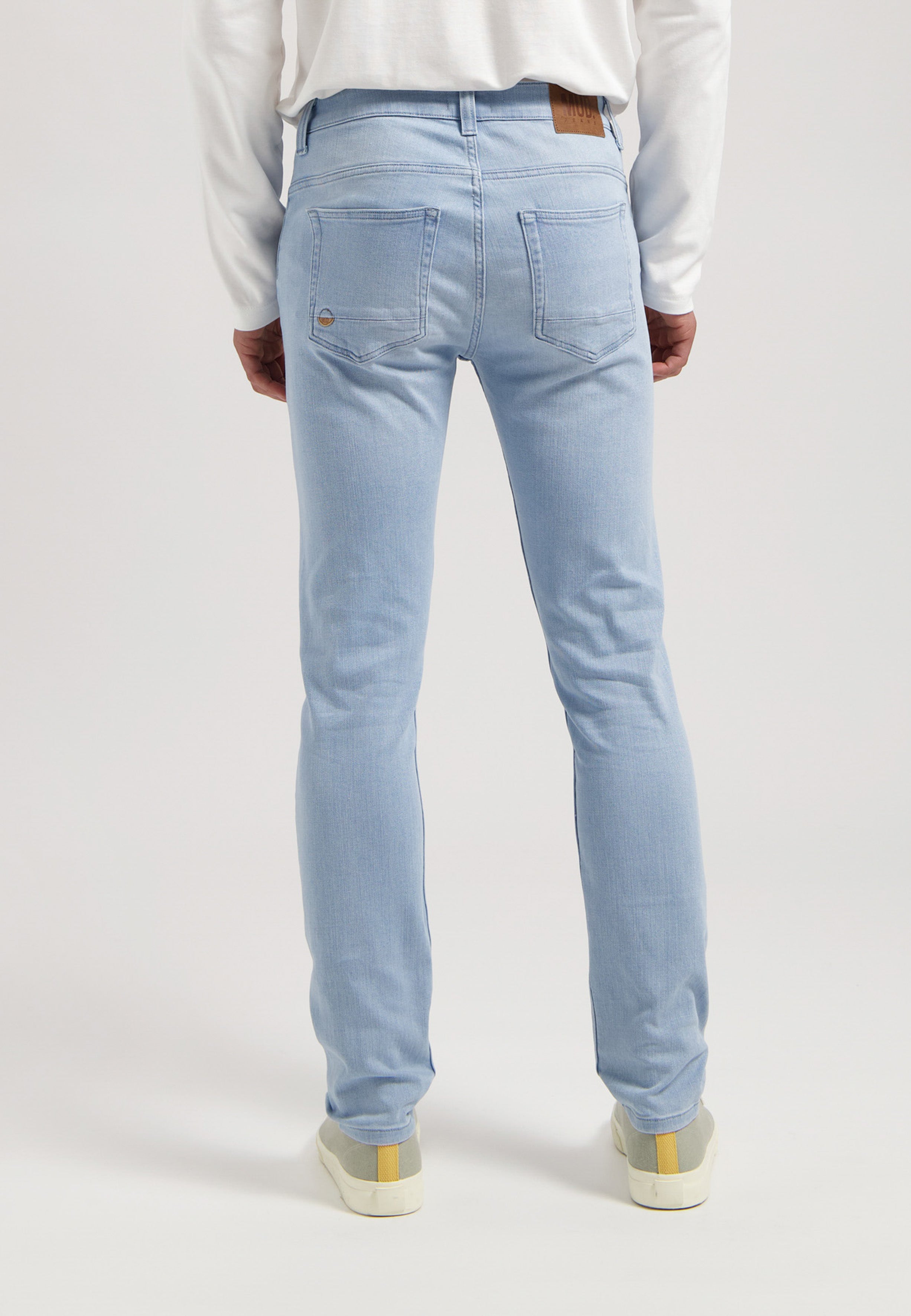 Sustainable MUD Jeans made from organic cotton, in a dark blue wash, paired with a classic gray sweater for an ethical style.