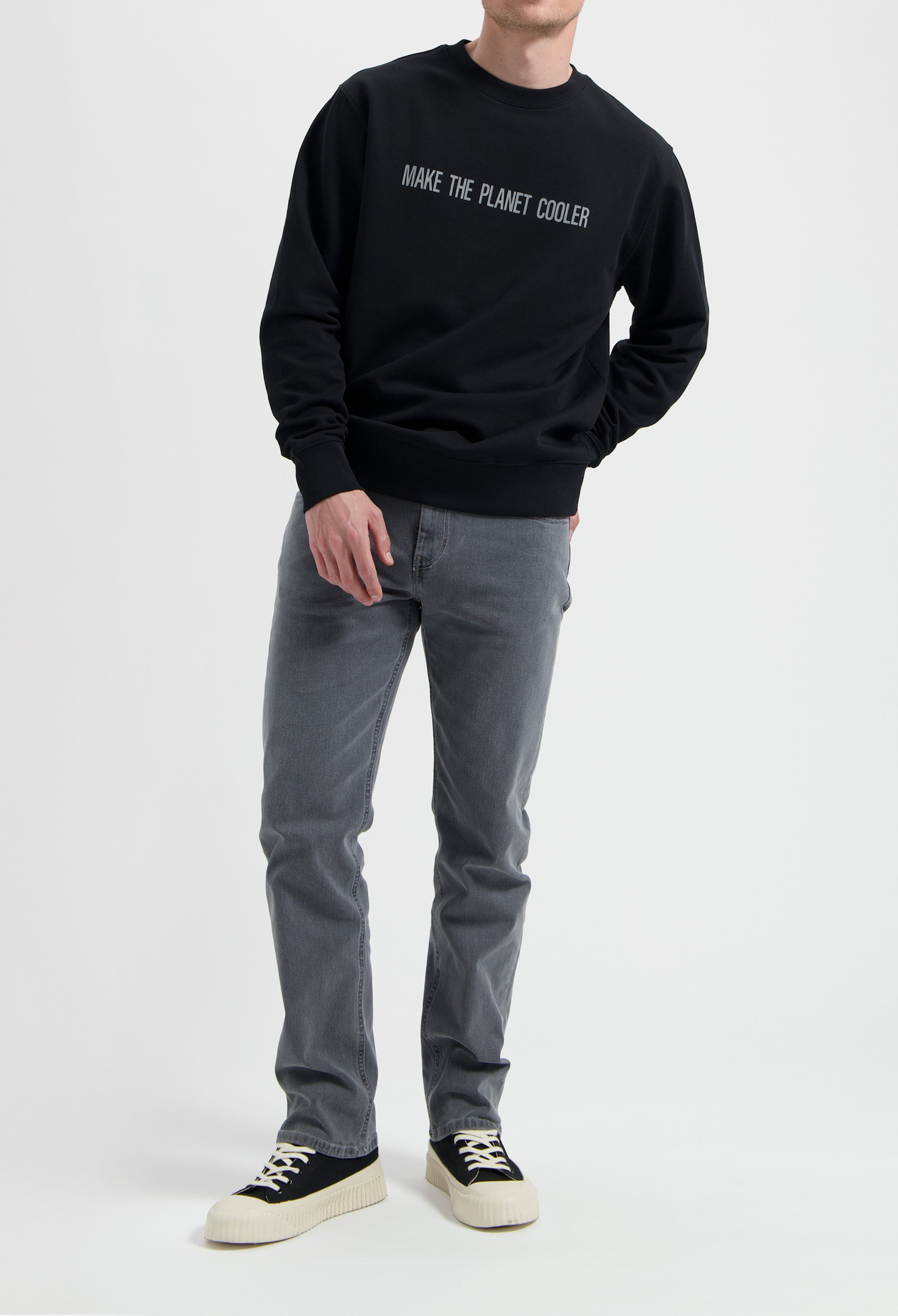 Sustainable MUD Jeans in gray denim, crafted from organic cotton, paired with a black sweatshirt promoting eco-awareness.