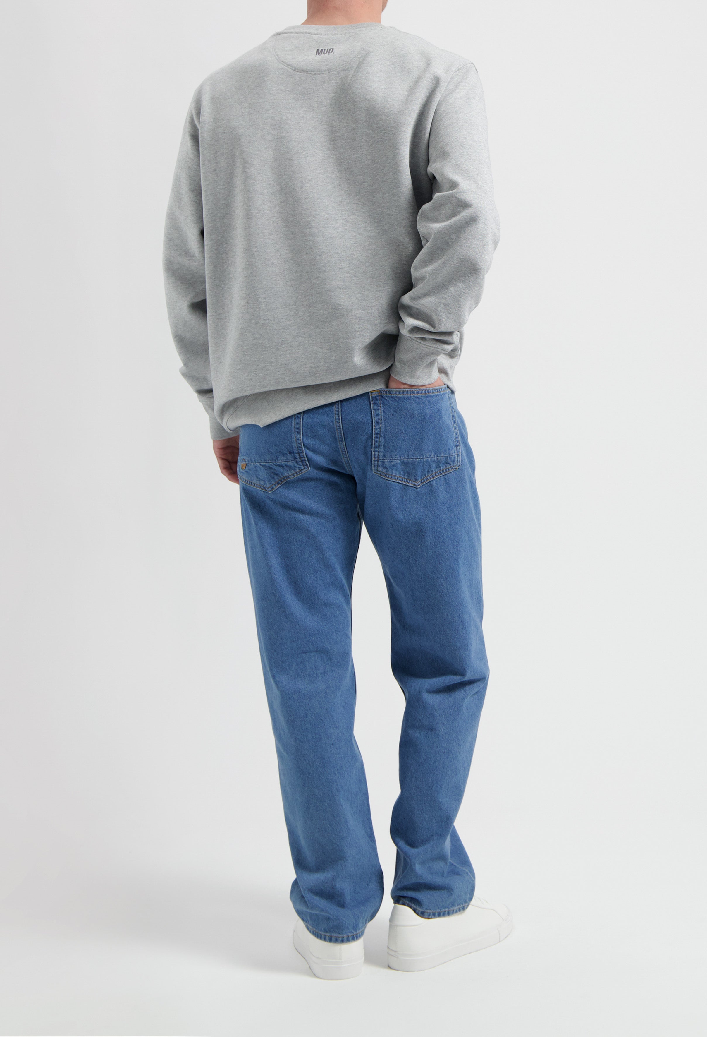 Sustainable MUD Jeans in blue denim, eco-friendly design, paired with a gray sweatshirt, showcasing ethical fashion.
