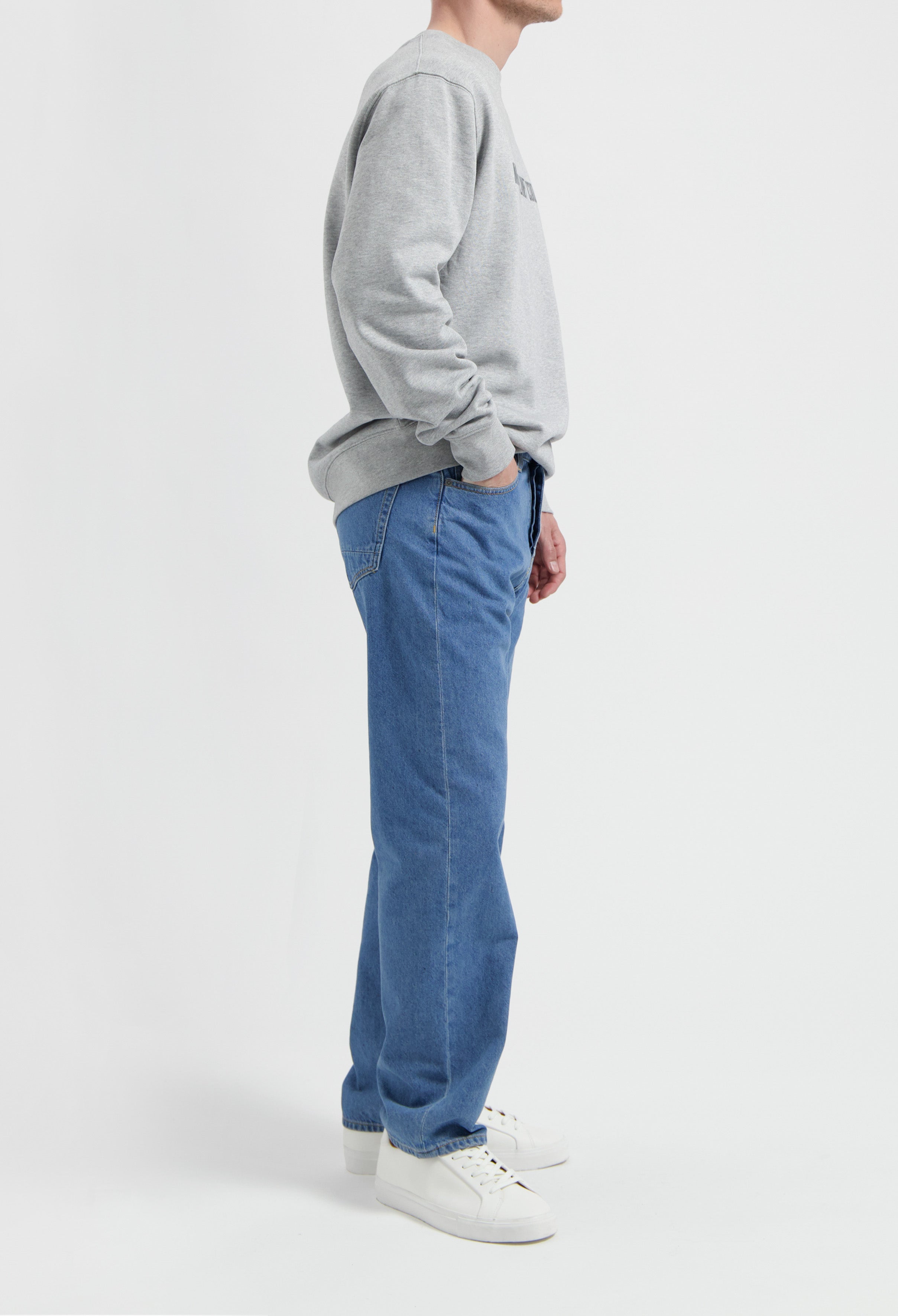 Sustainable MUD Jeans crafted from ethical materials, featuring blue denim in a relaxed fit, styled with a gray sweater.