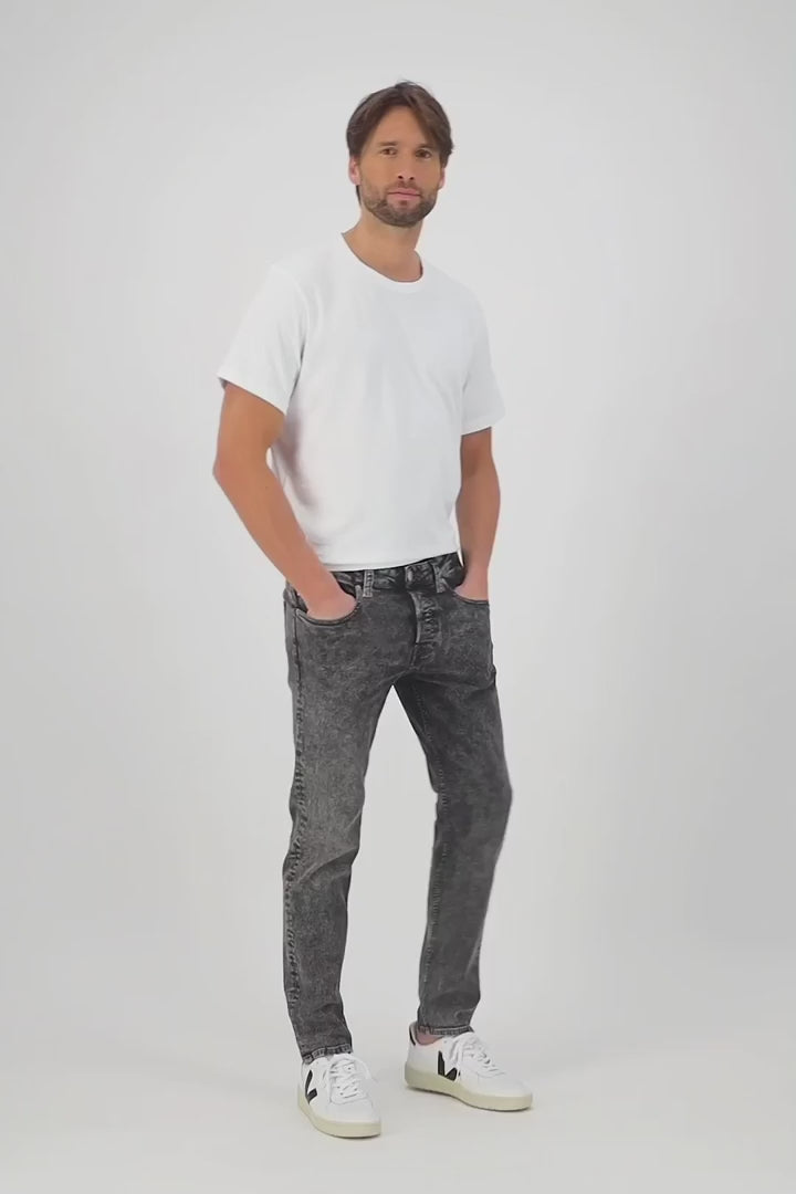 Sustainable MUD Jeans in deep blue denim, ethical cotton fabric, classic straight fit, paired with casual sneakers.