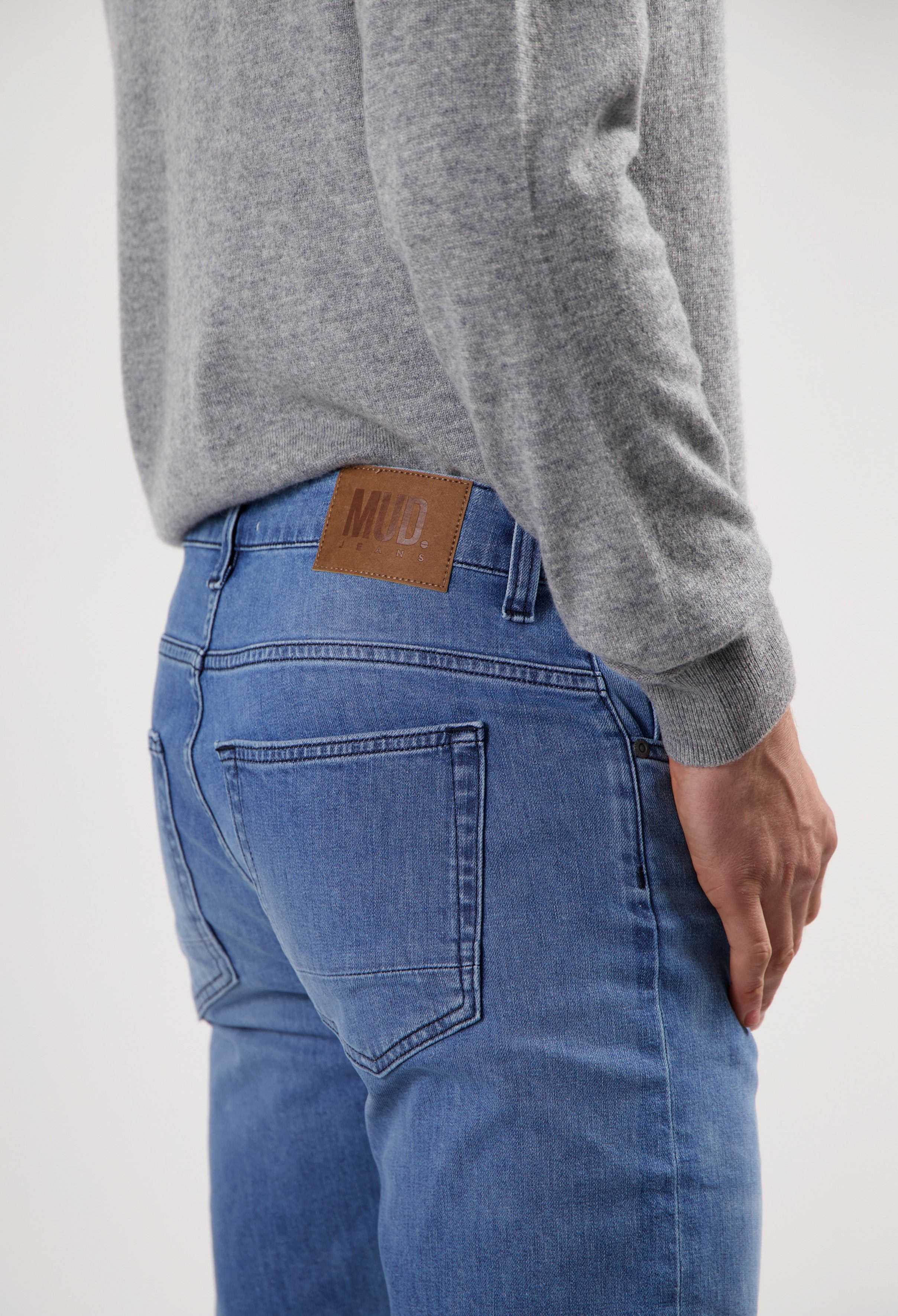 Sustainable MUD Jeans in dark denim, crafted from organic cotton, worn with a white tee, emphasizing ethical fashion.