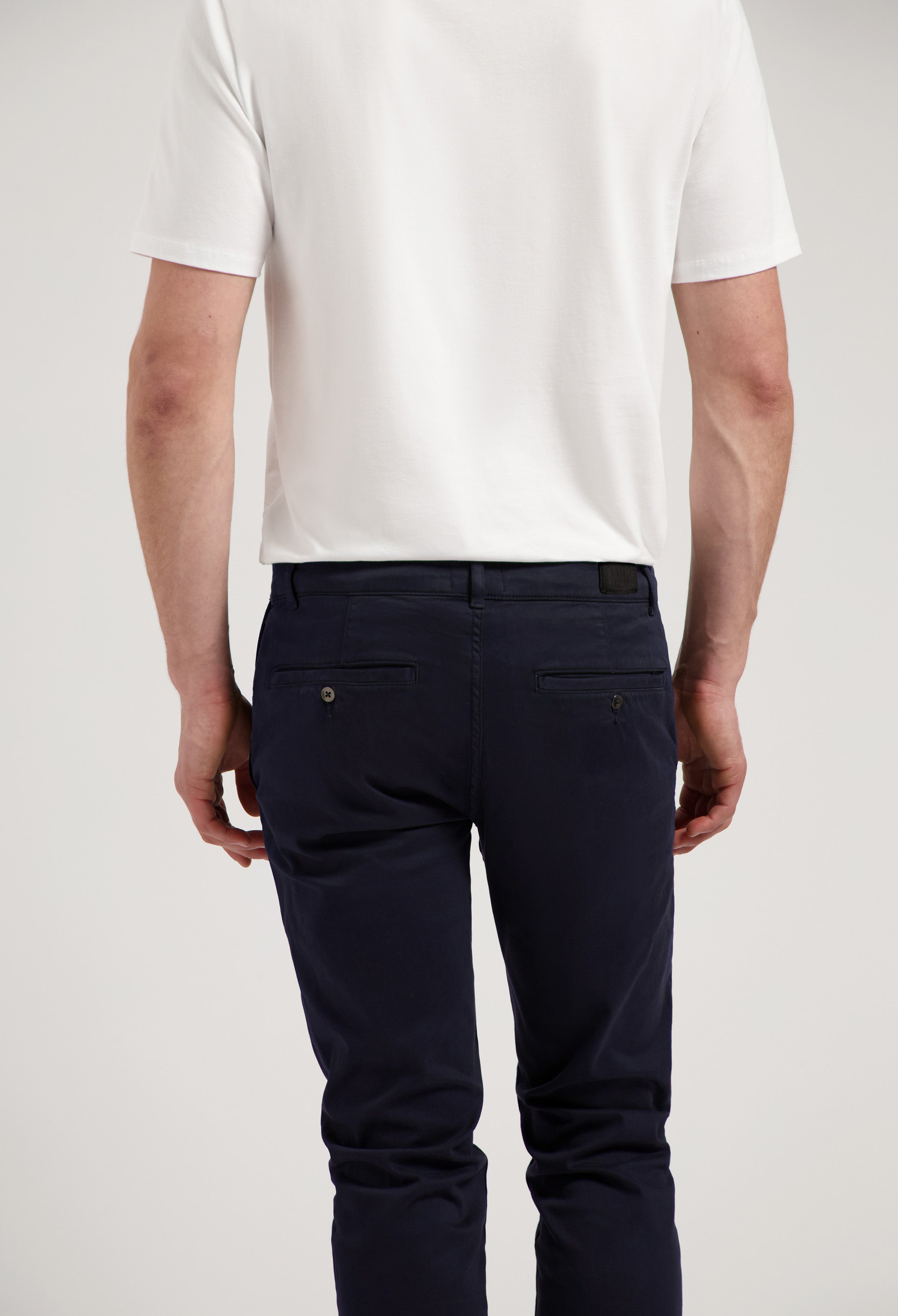 Sustainable MUD Jeans in white denim, crafted ethically from organic cotton, paired with a navy blue shirt.