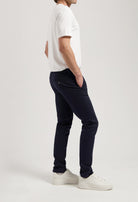 Sustainable MUD Jeans in white denim, crafted ethically, paired with a navy t-shirt and black loafers.
