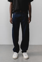 Sustainable MUD Jeans with a modern fit in deep black denim, paired with a casual gray sweater and white sneakers.