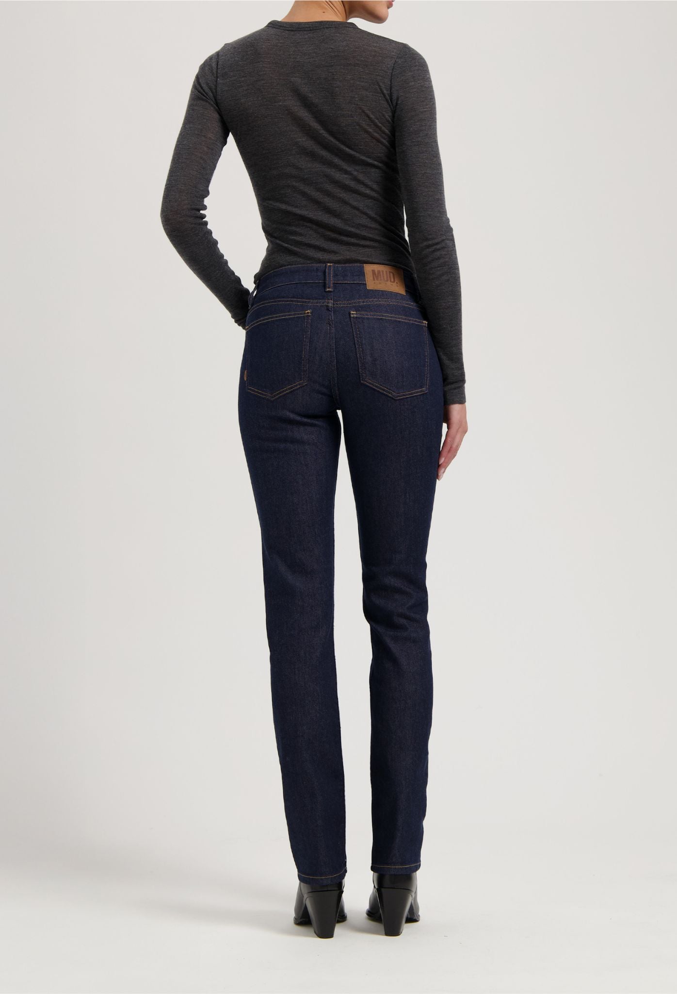 Dark blue slim-fit jeans by MUD Jeans, crafted from sustainable organic cotton, paired with a charcoal gray long-sleeve top.