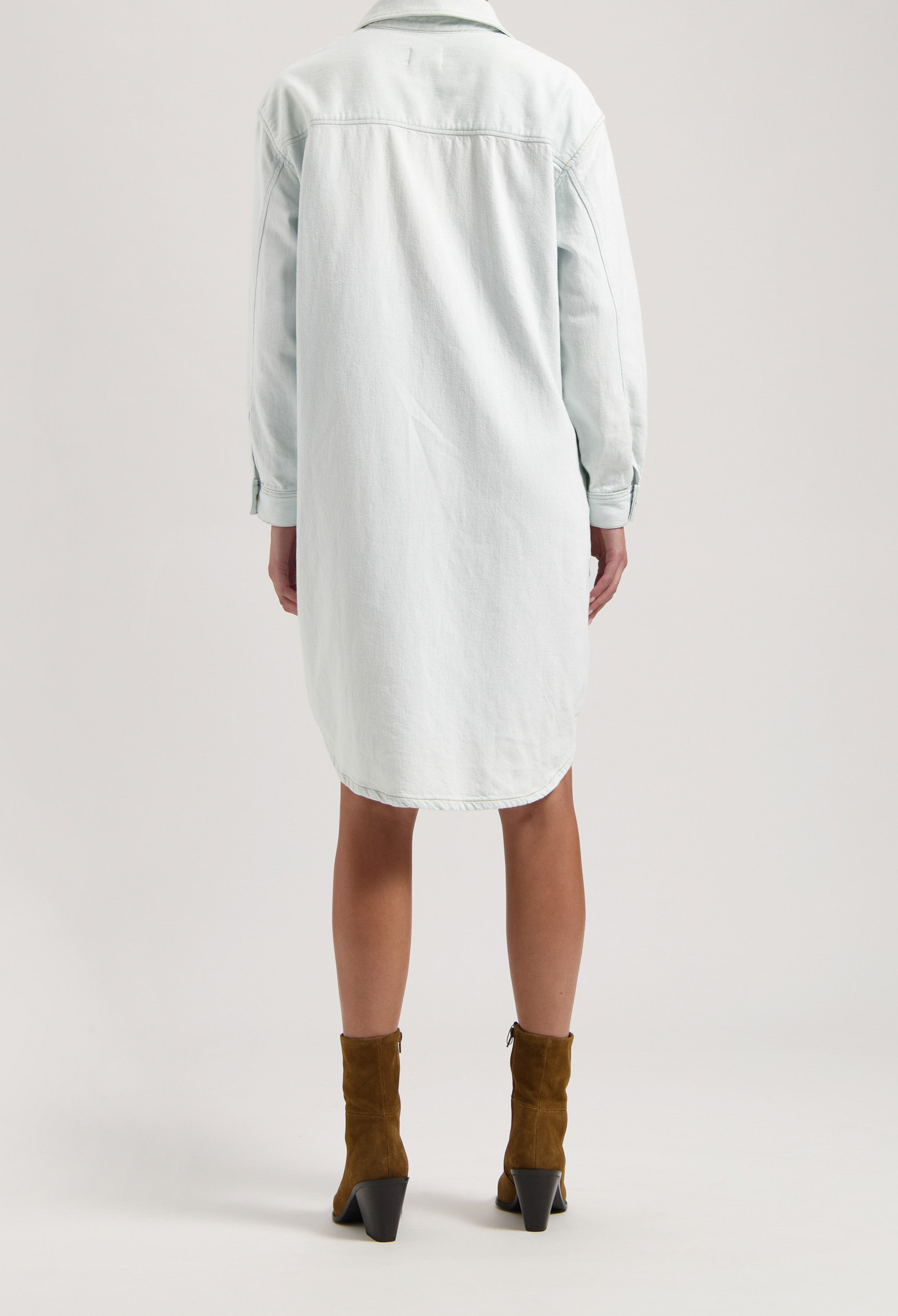 Back view of a light blue denim shirt dress paired with brown suede ankle boots, emphasizing casual style fashion.