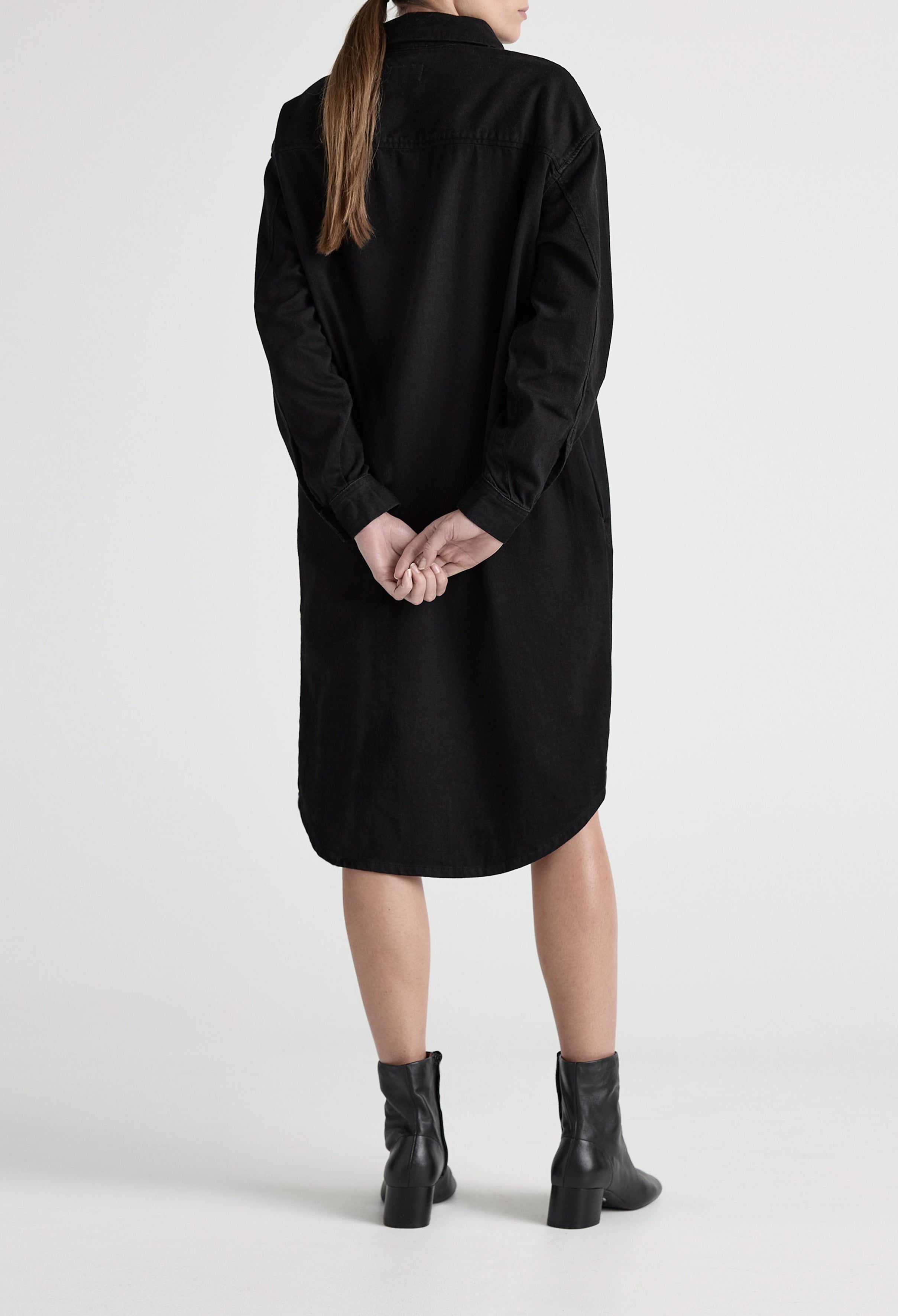 Black shirt dress with long sleeves, worn with black ankle boots, showcasing a casual and stylish outfit from behind.